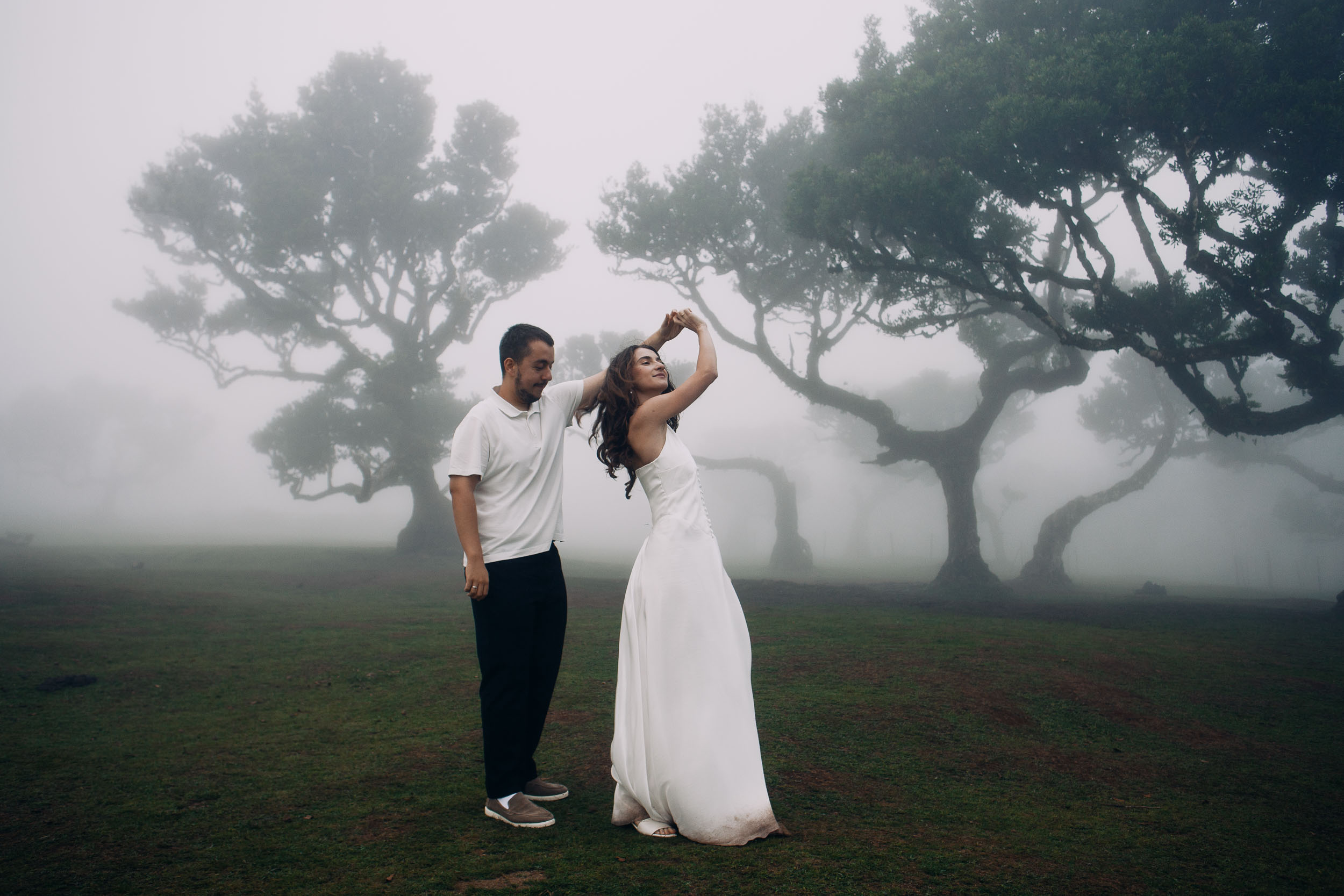 He turns her under his raised arm on the wet grass, Fanal Forest, Madeira