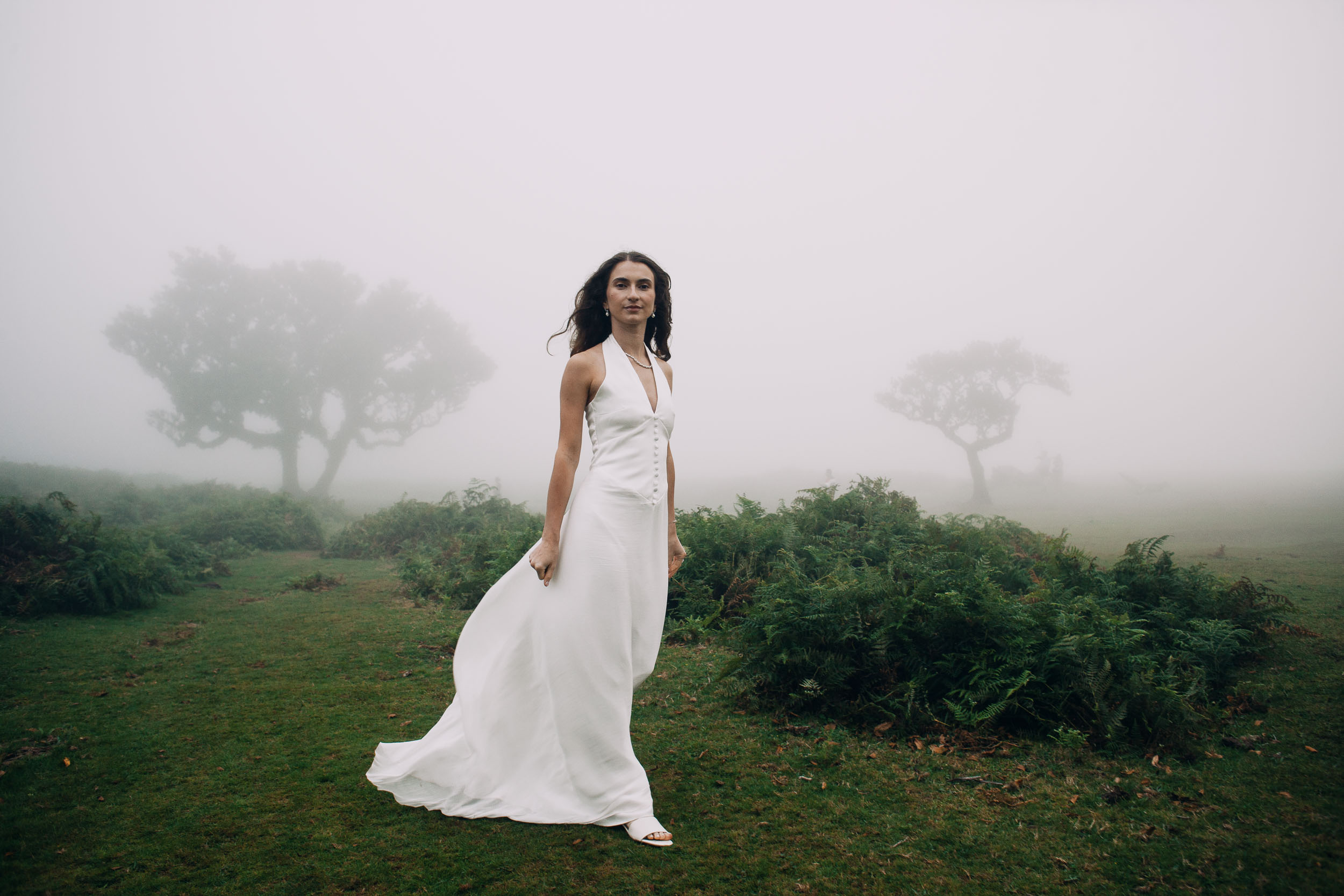 Woman standing with her dress swept to one side, laurels behind, Fanal Forest, Madeira