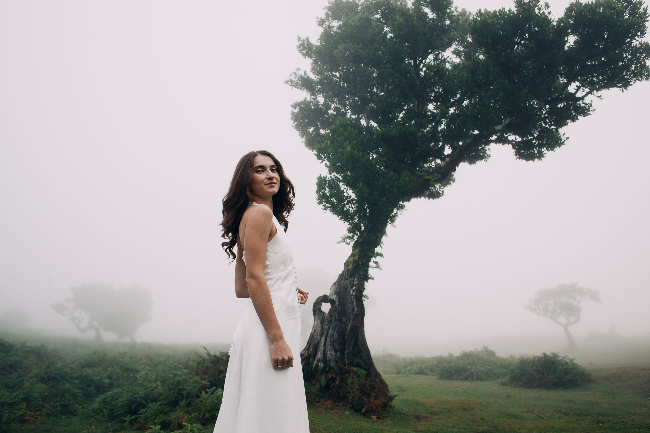 She turns and smiles over her shoulder, laurel grove behind, Fanal Forest, Madeira