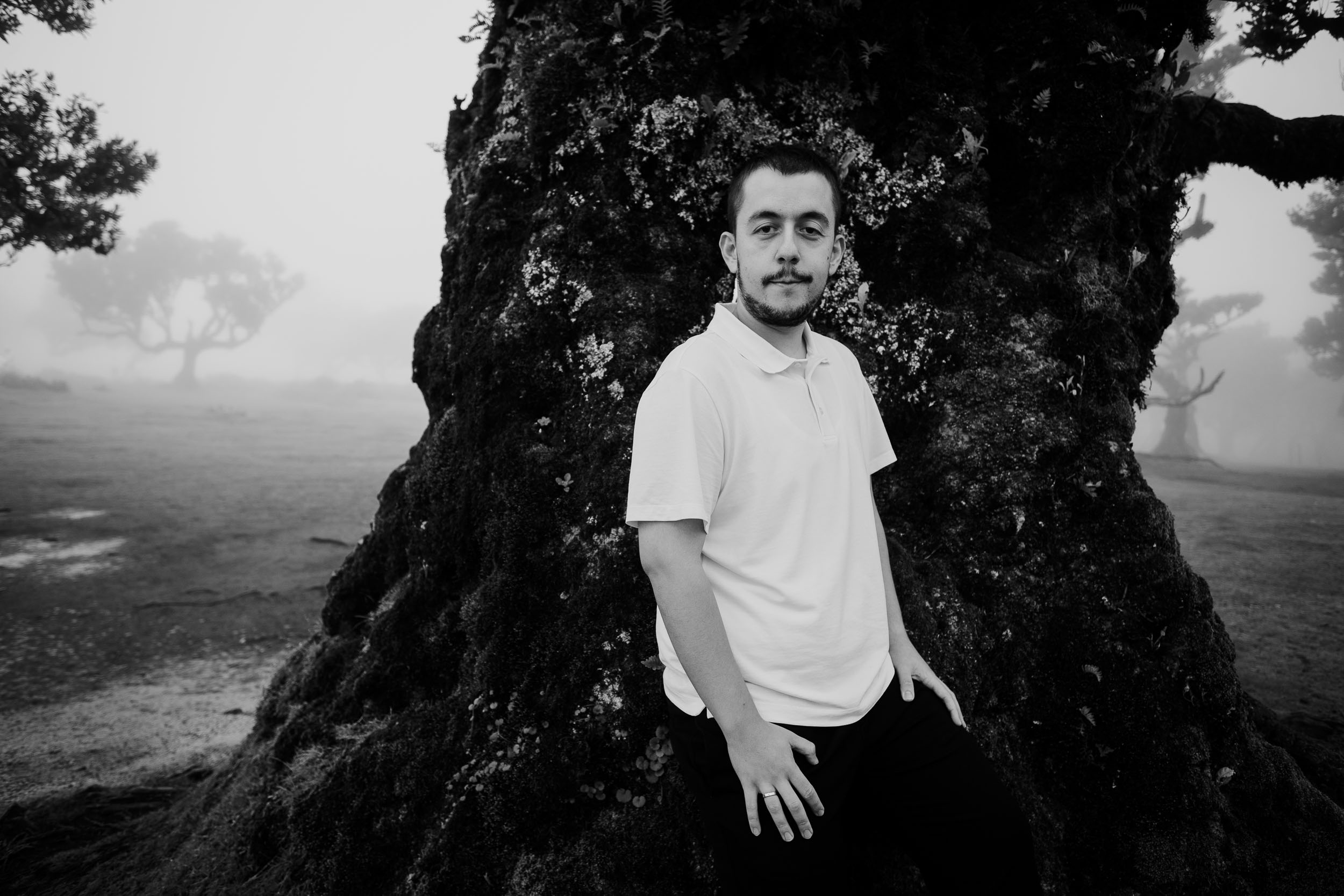 Black and white portrait of him against a mossy laurel trunk, Fanal Forest, Madeira