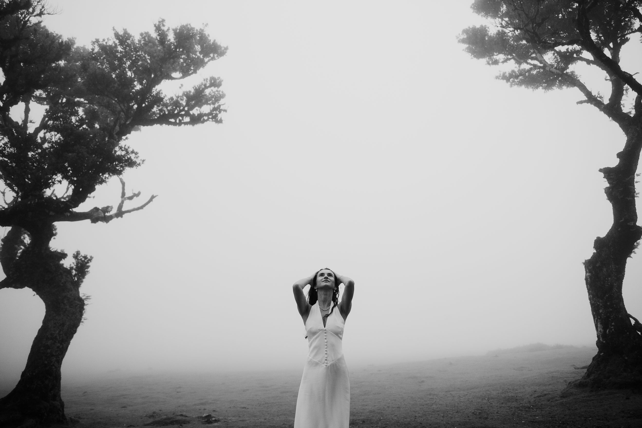 Black and white frame of her alone between two laurels, hands in her hair, Fanal Forest, Madeira