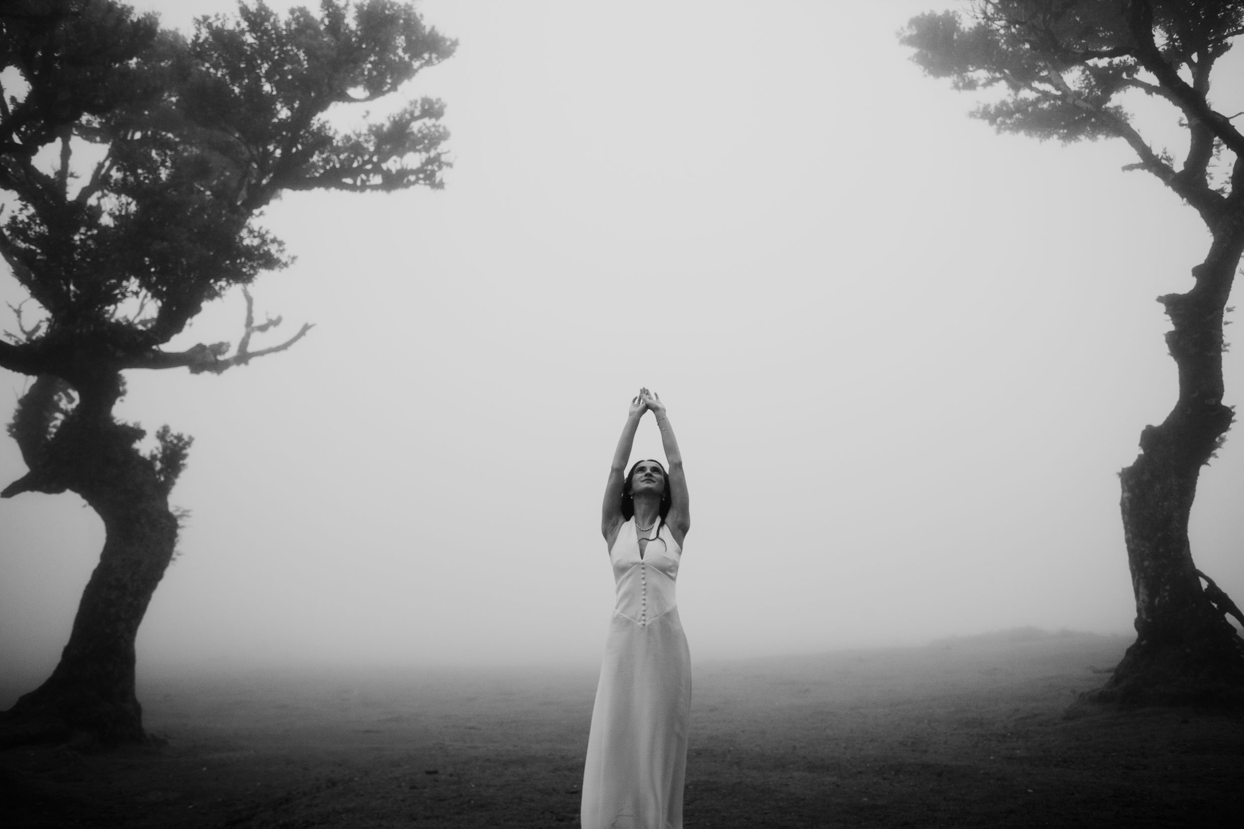 Black and white frame, arms raised, fog between the trees, Fanal Forest, Madeira