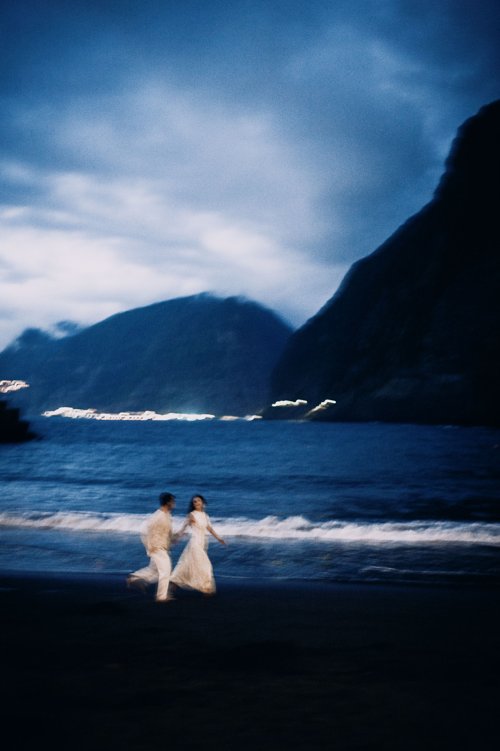 Couple running along the shoreline as the last light leaves the sky, Seixal Beach, Madeira