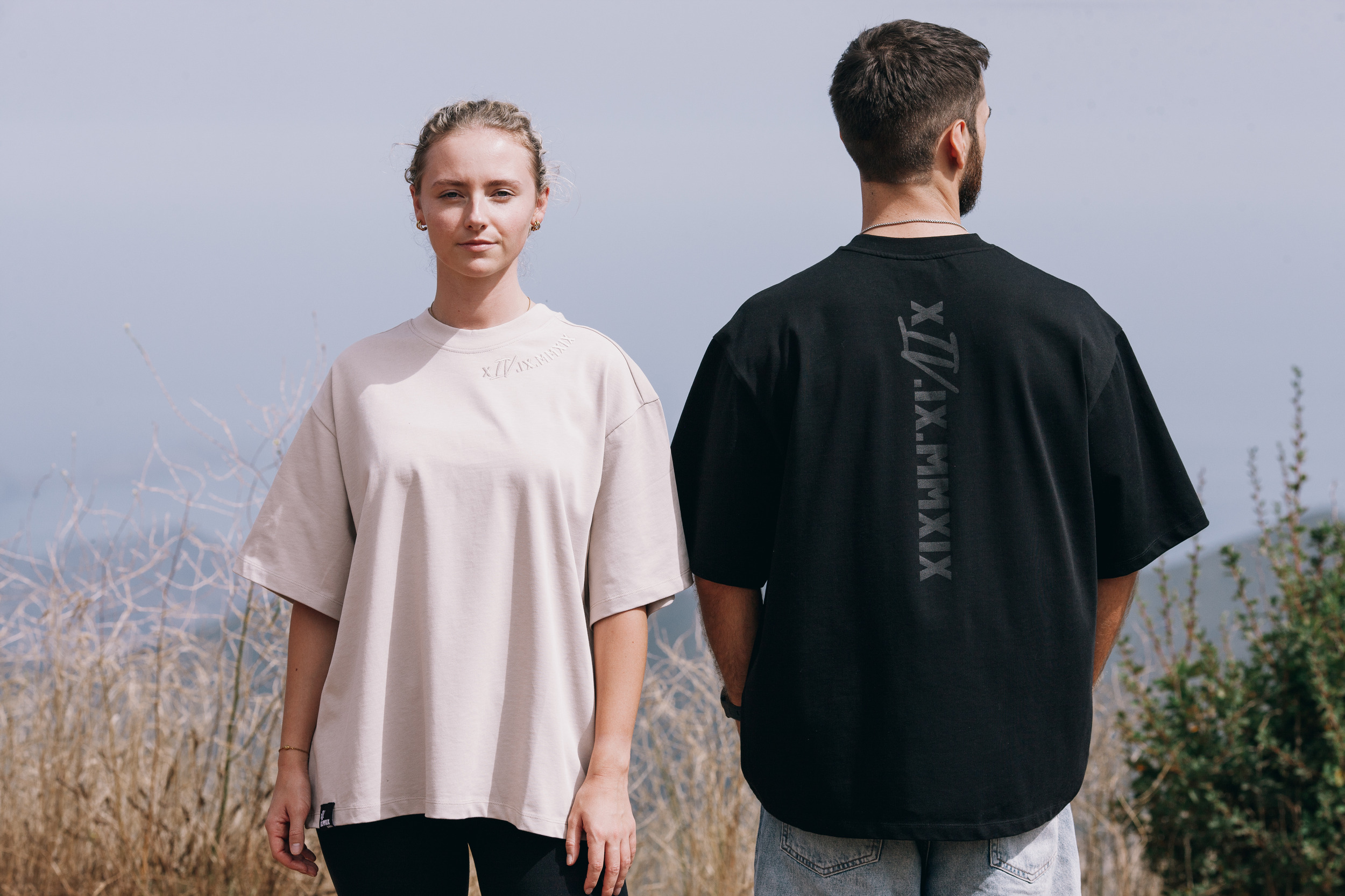 Front of the beige oversized tee beside the back print of the black one, Madeira highlands