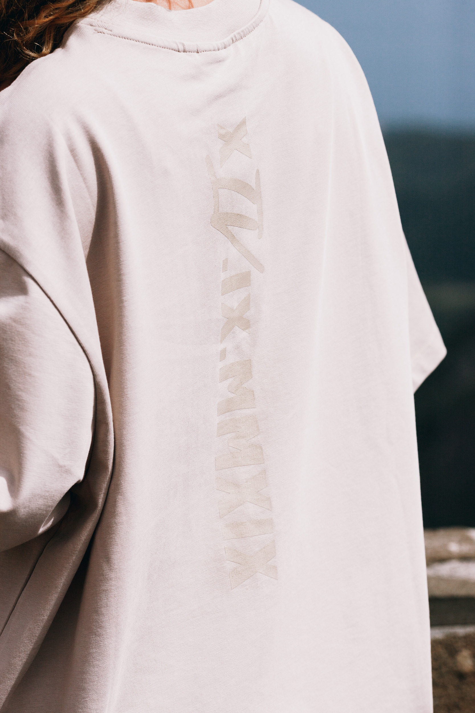 Shoulder detail of the beige tee with the tonal roman numeral embroidery