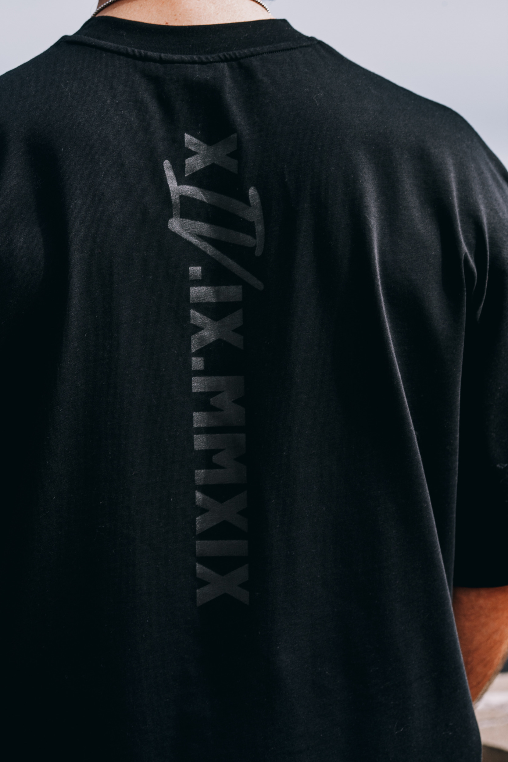 Back of the black oversized tee with the vertical roman numeral print, Madeira highlands