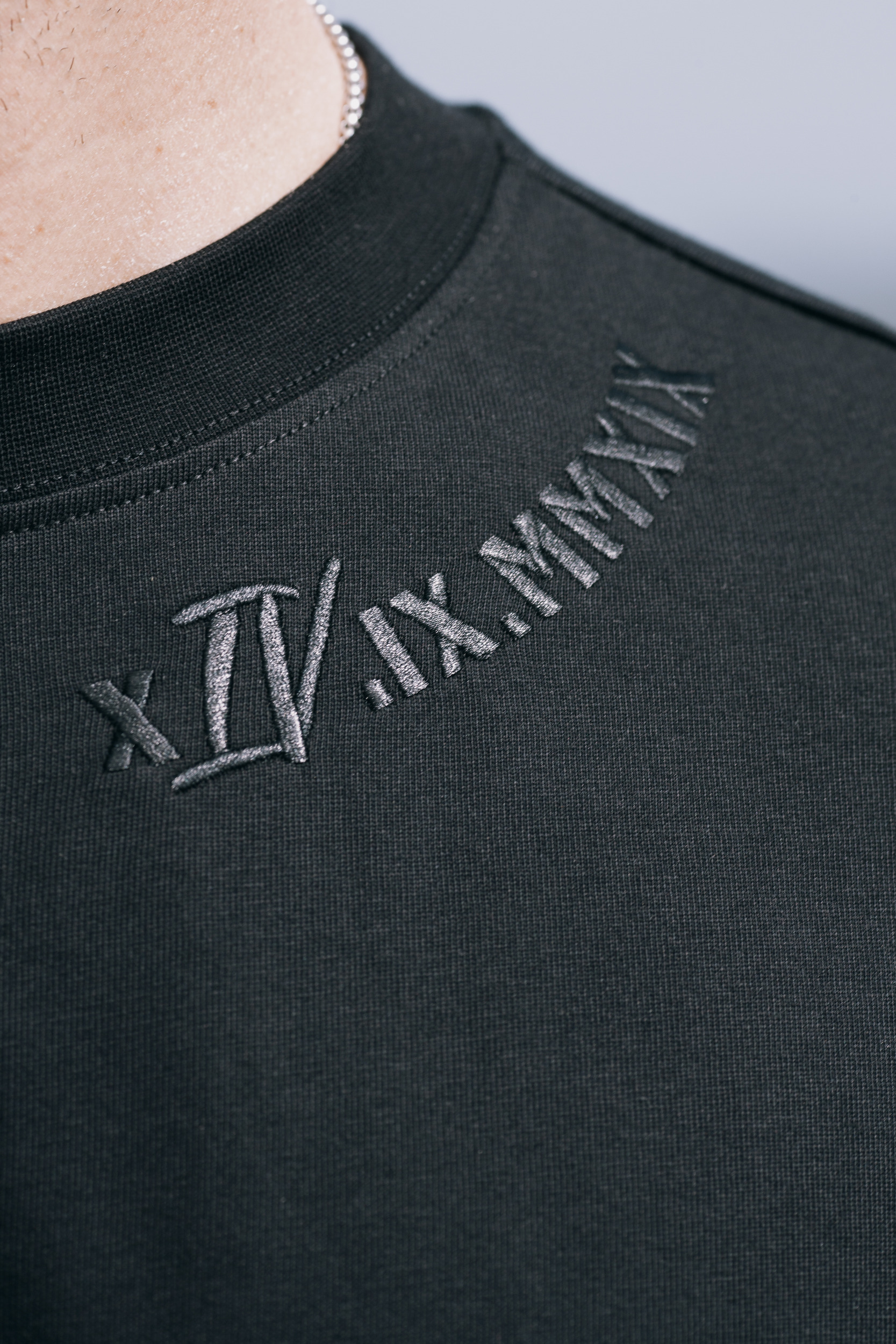 Collar embroidery on the black tee, black thread on black cotton, close detail