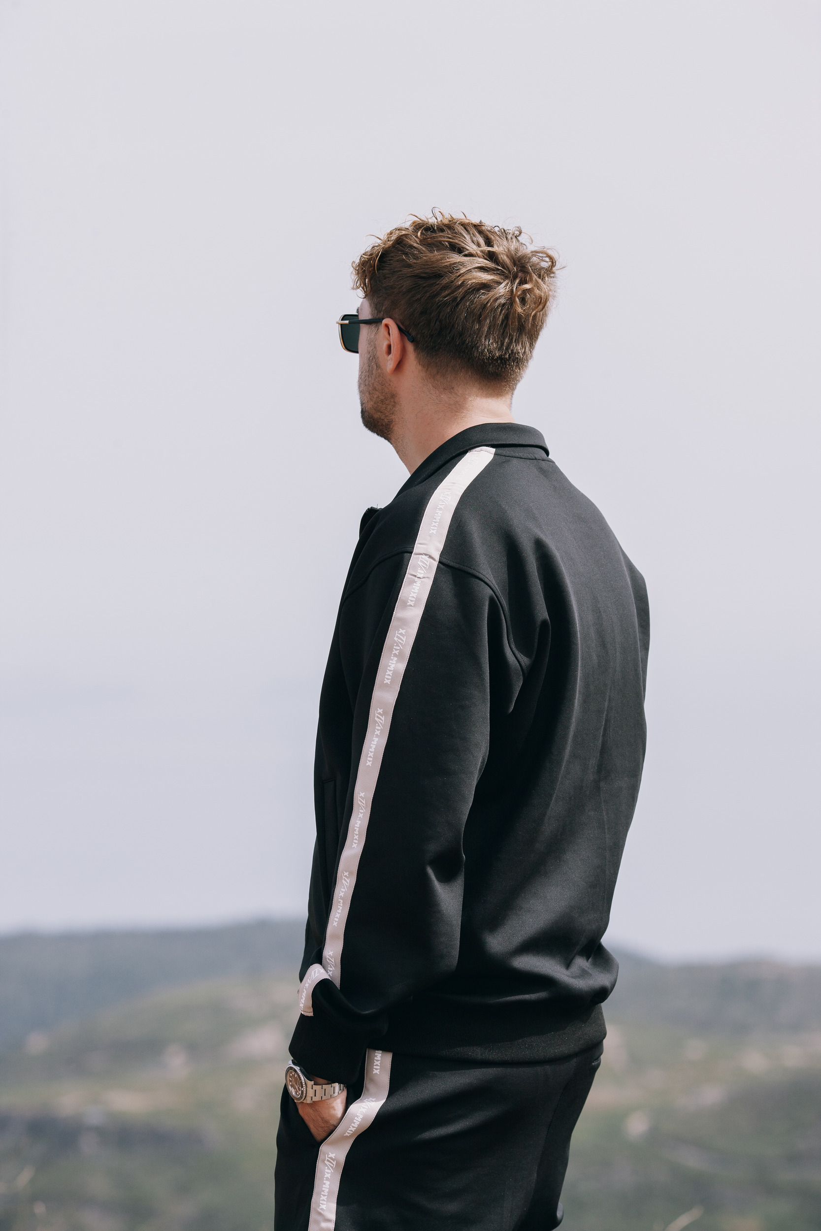 Back view of the black track suit with the side stripe running down the arm and leg, Madeira