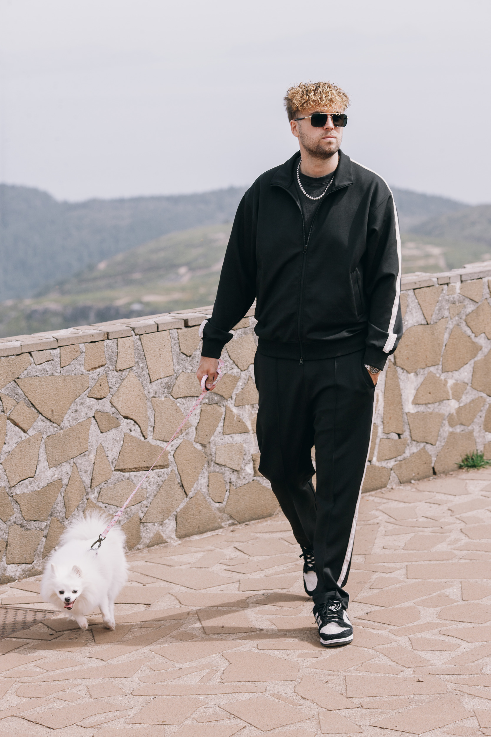 Man walking along the paved viewpoint with the white dog beside him, Madeira