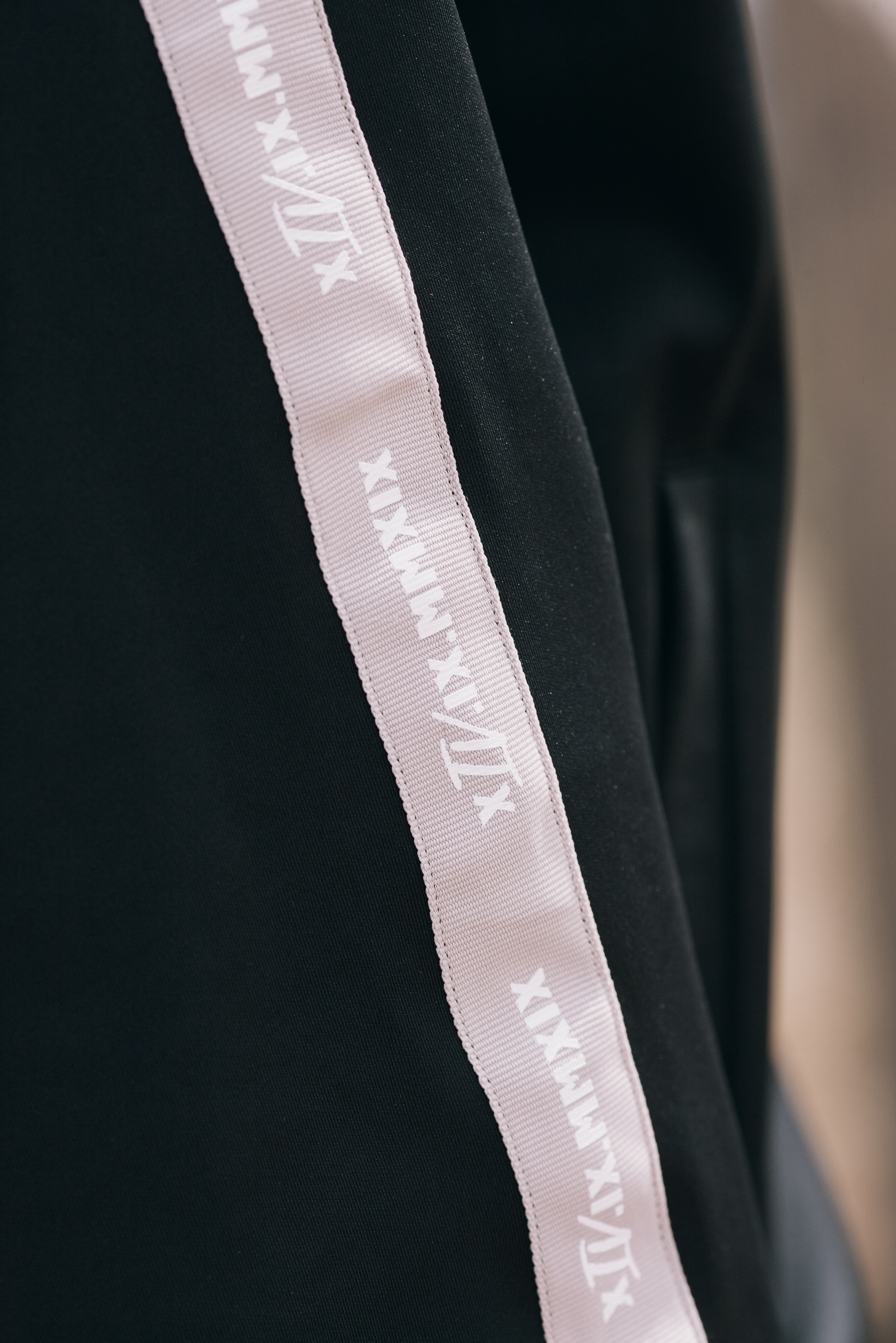 Side stripe of the track pants with the roman numerals printed along it, close detail