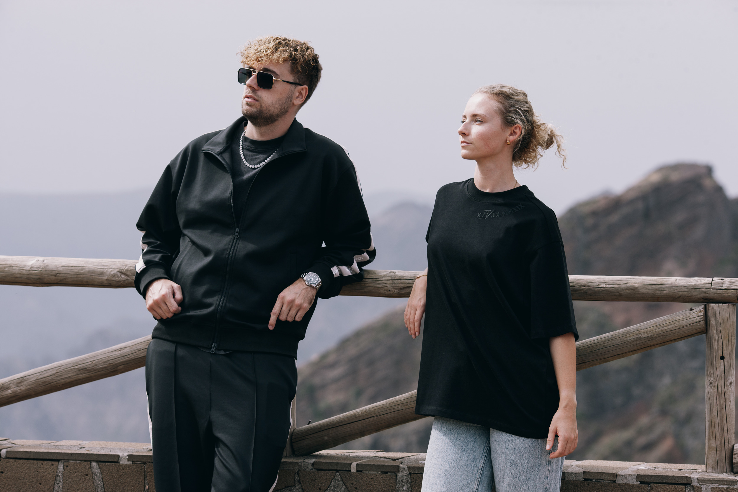 Man and woman standing at a wooden railing above the cliffs near Pico do Arieiro, Madeira