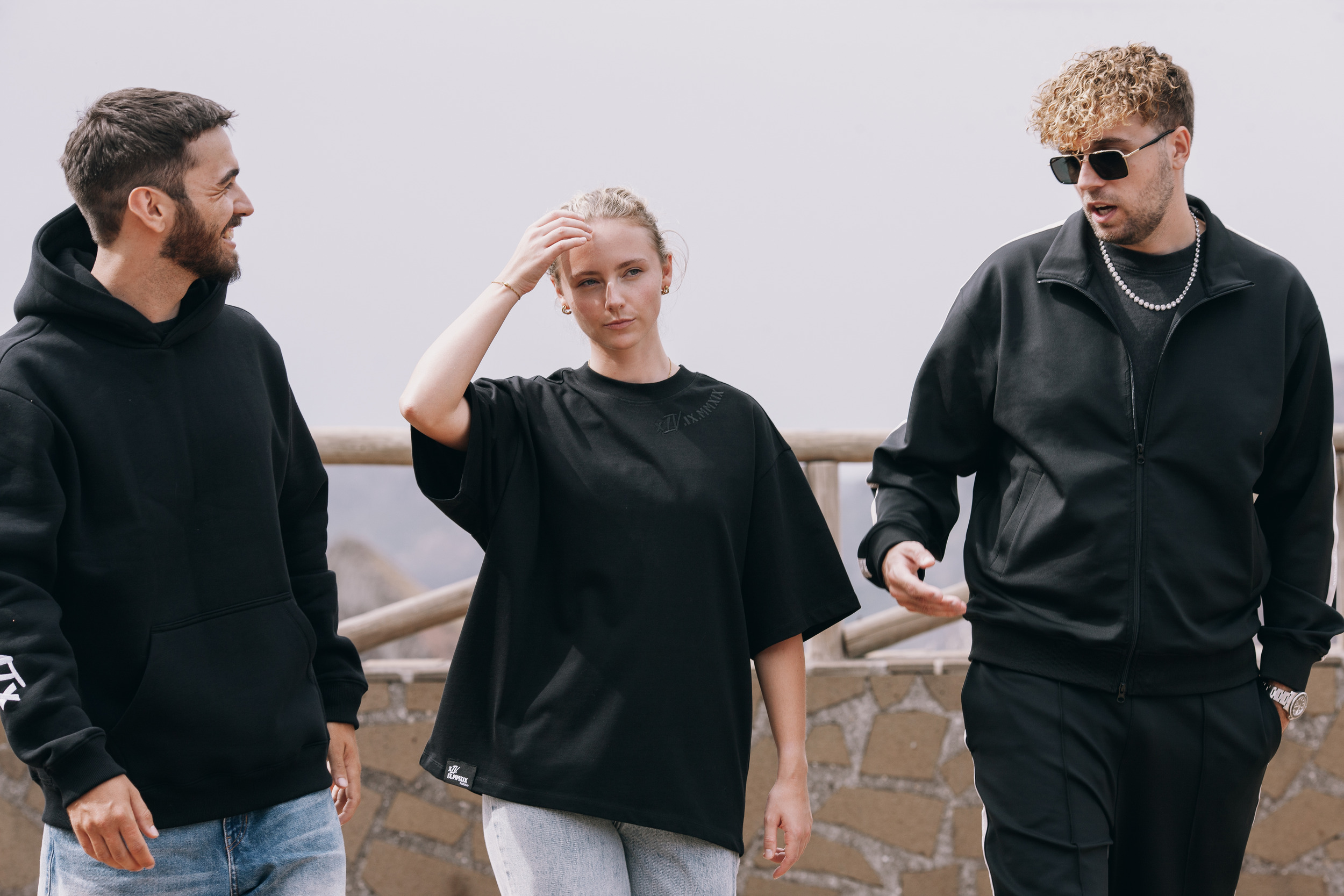 Woman pushing her hair back between two men at the railing, Madeira