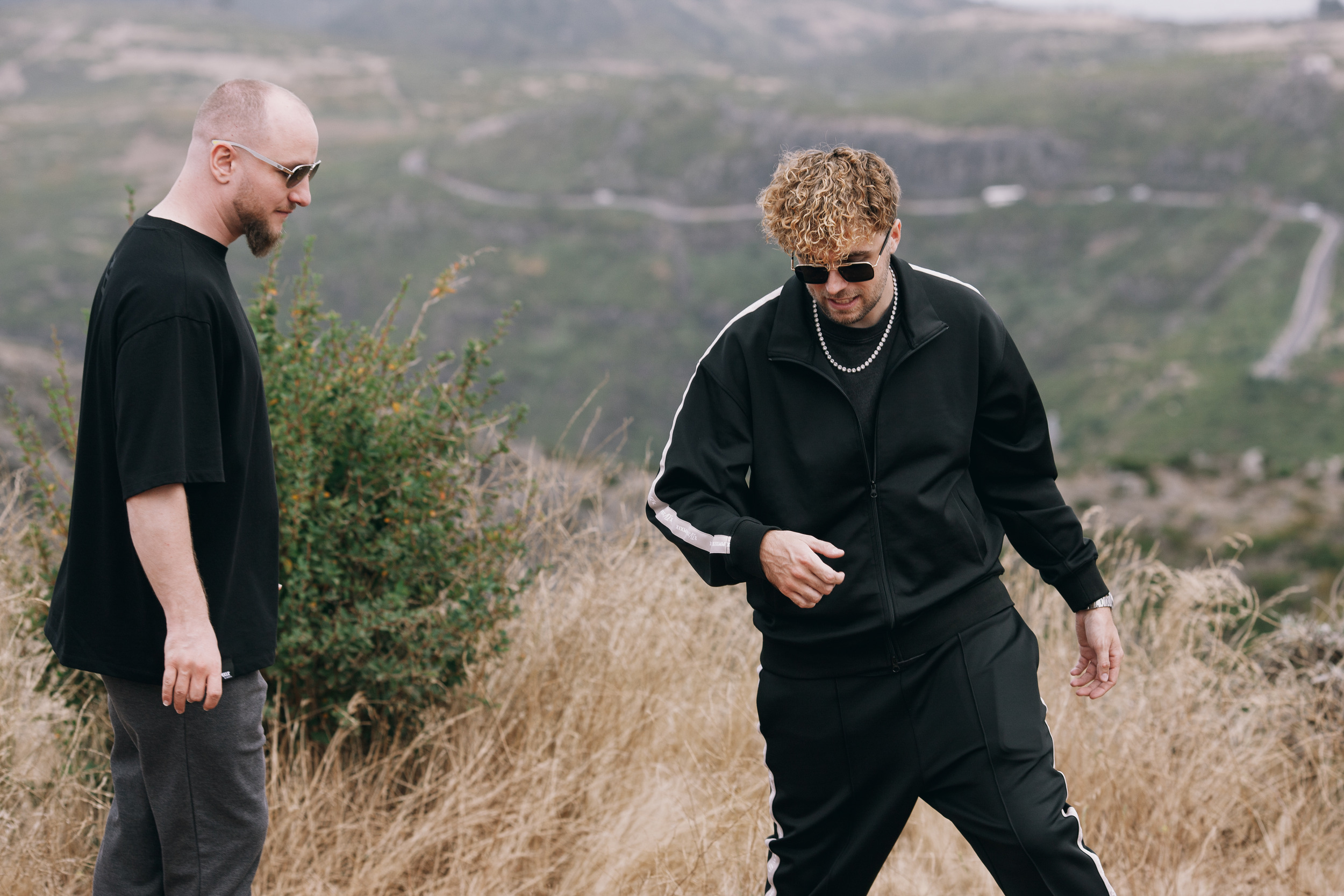Two men walking through the dry grass in black, Madeira highlands