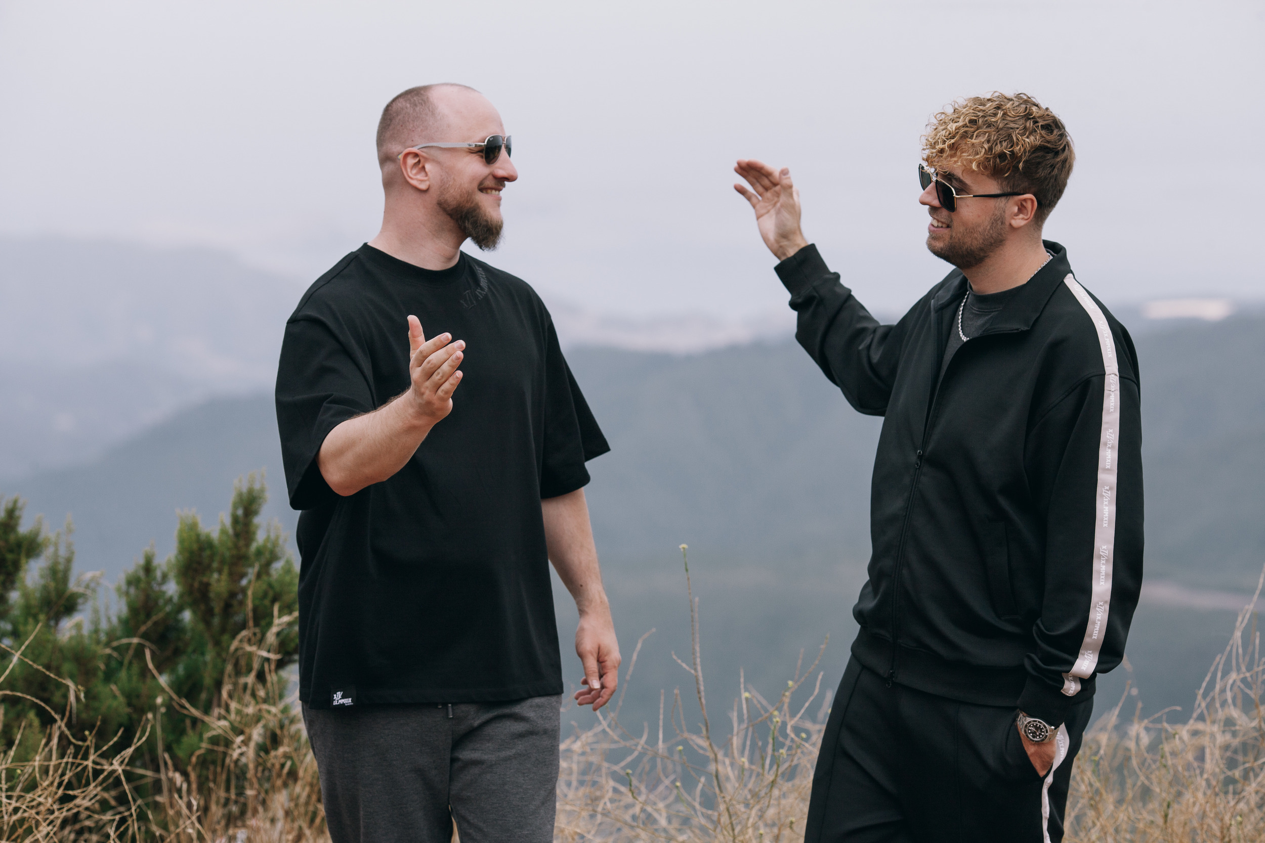 Two men talking, one gesturing toward the valley, Madeira highlands