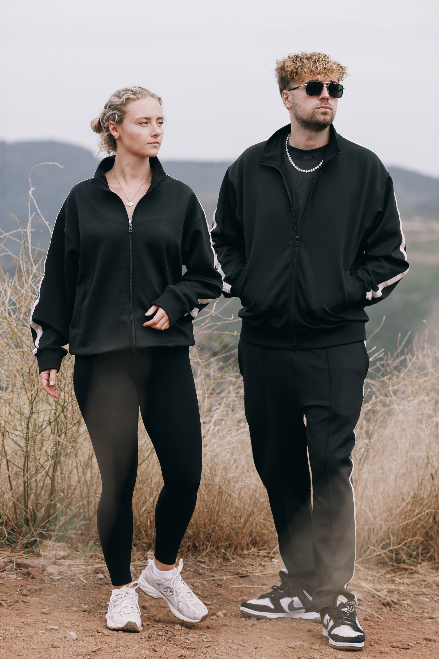 Pair walking on the dirt at the viewpoint in black track suits, Madeira