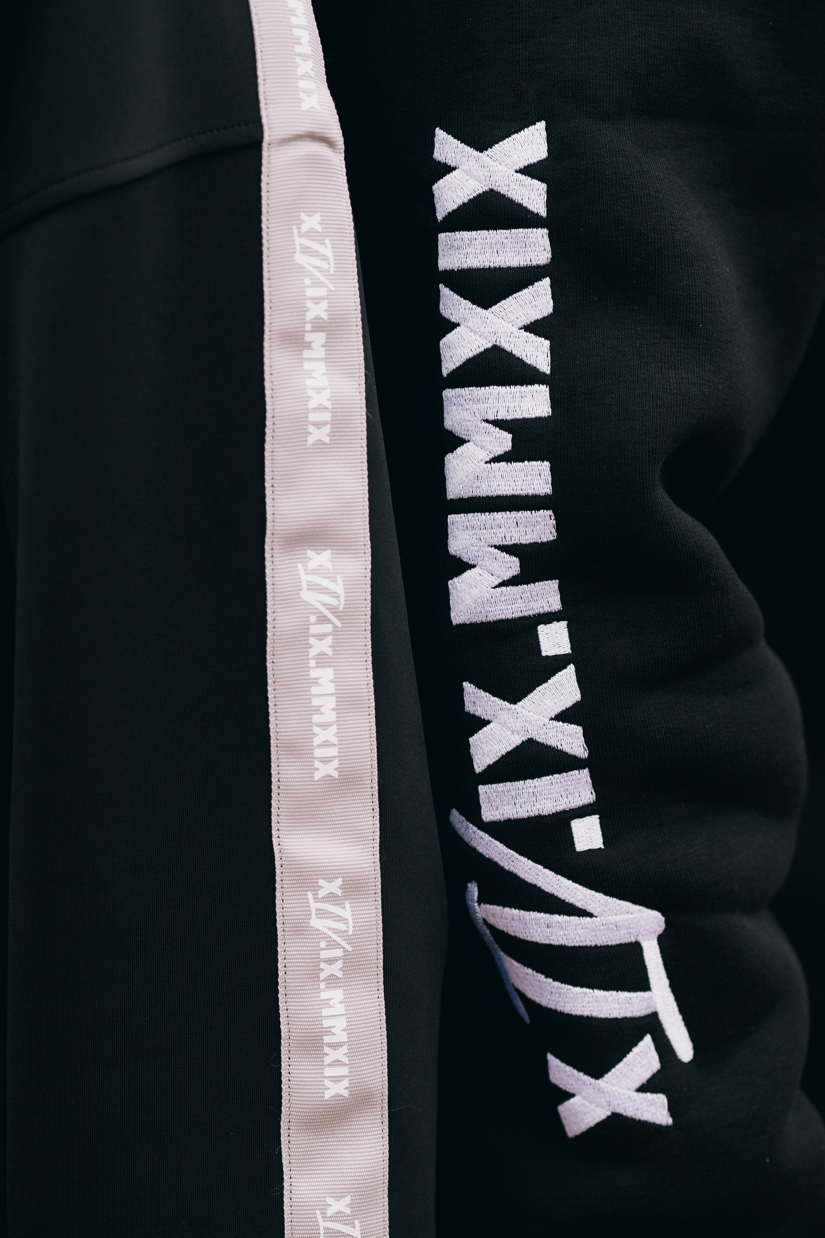 Roman numerals printed along the track pant stripe, close detail