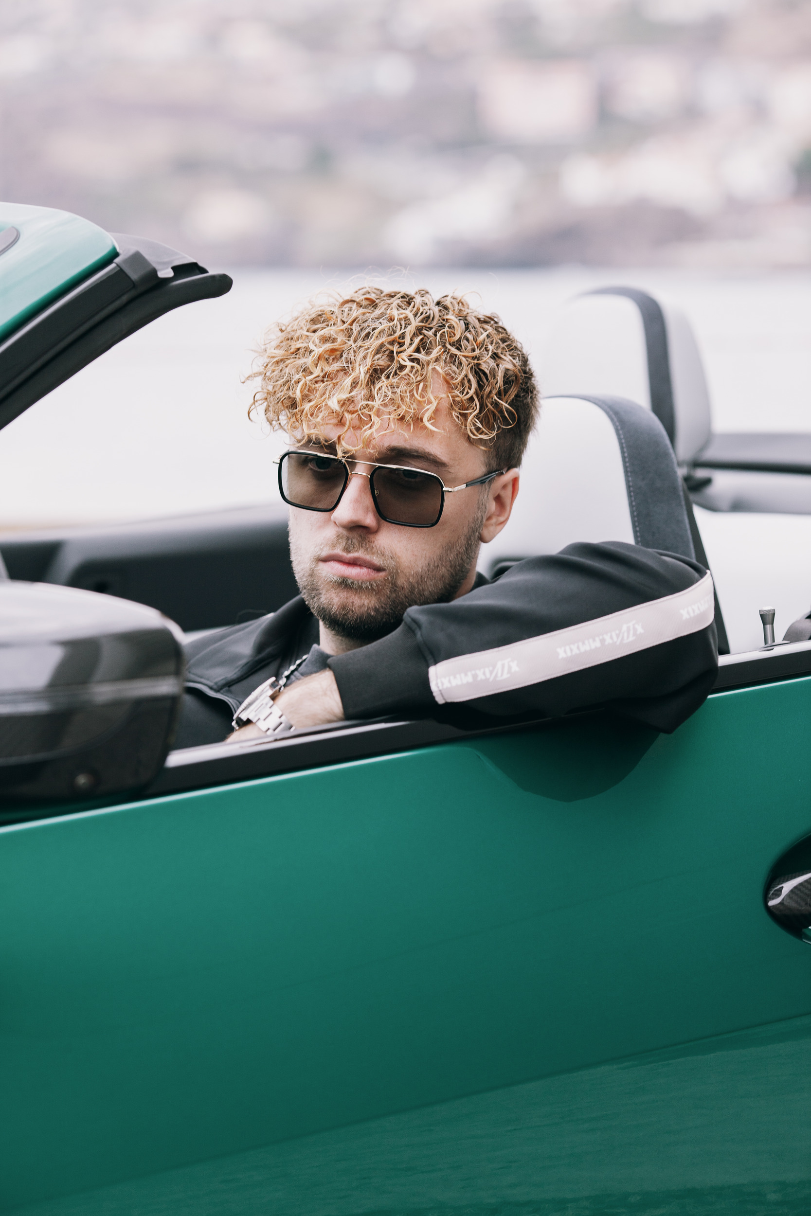 Model in the driver seat of the open convertible, arm over the door, Madeira