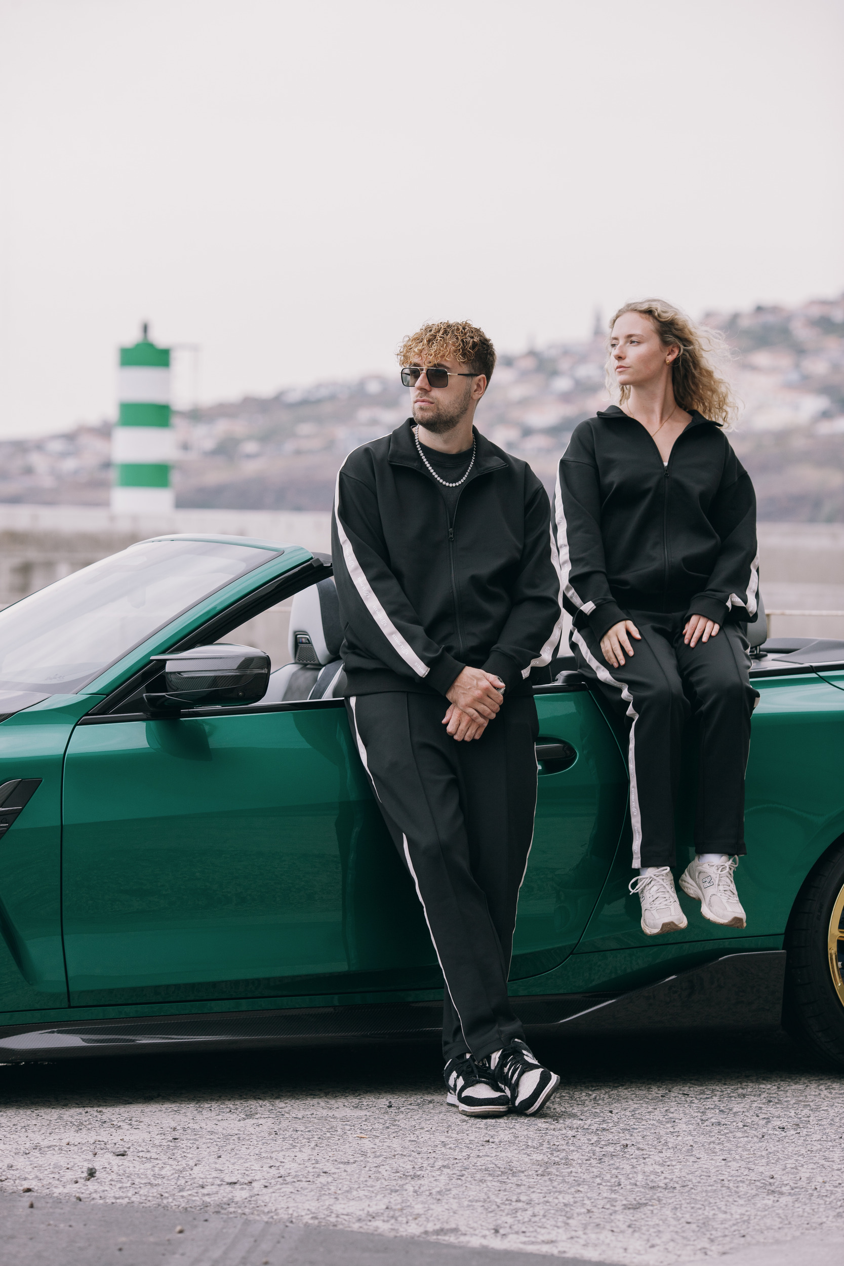 Two models beside the green convertible with the harbour behind them, Madeira