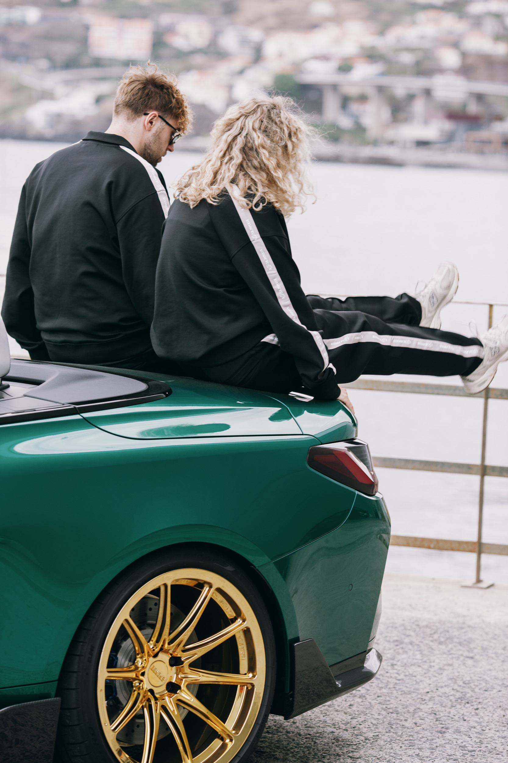 Two models sitting on the boot of the convertible above Funchal, Madeira