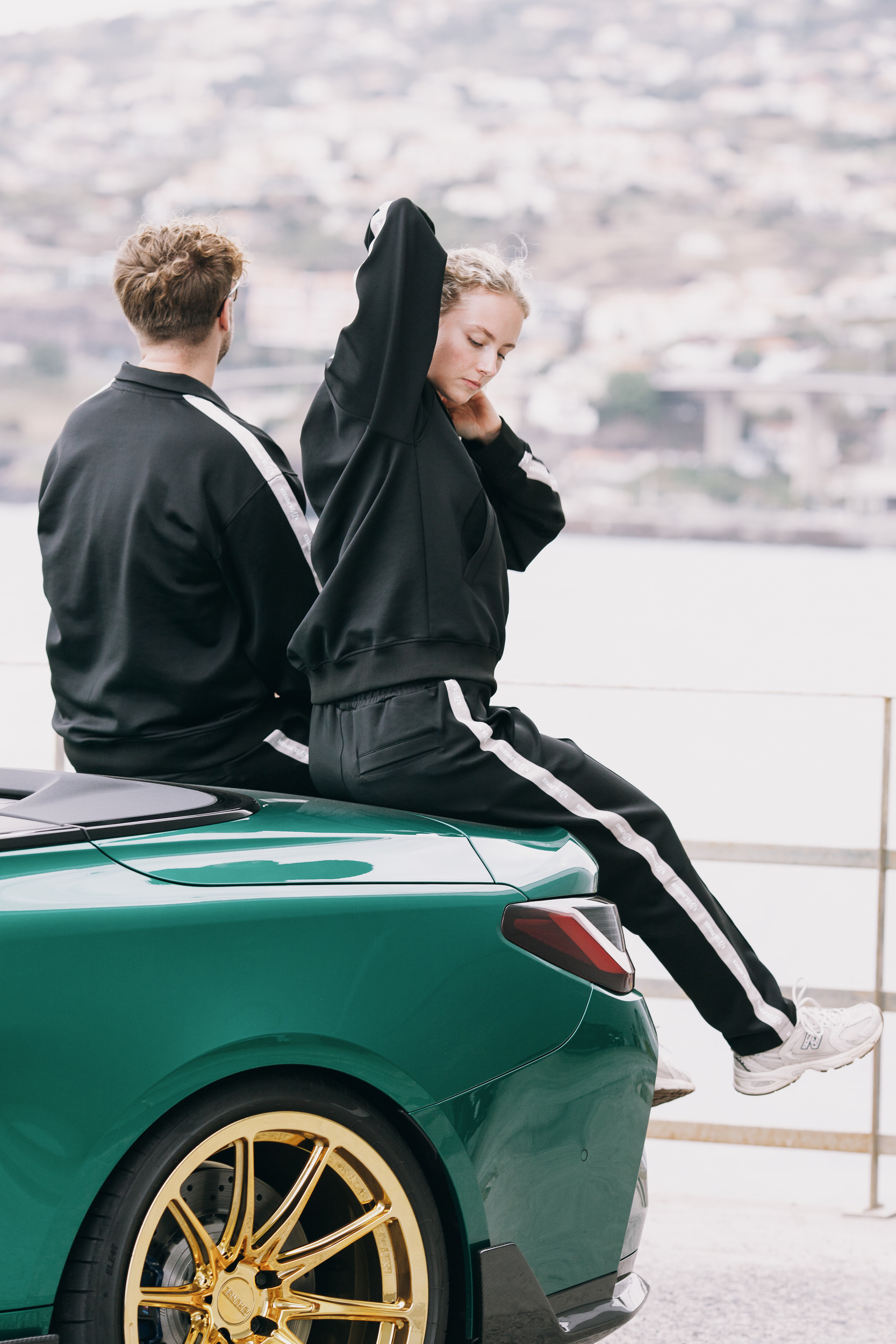 Woman pushing her hair back while sitting on the car, town behind, Madeira