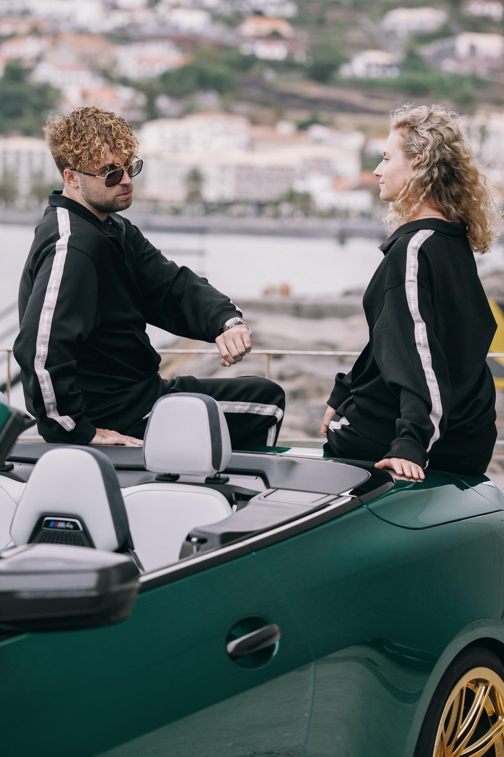 Two models by the open convertible with Funchal spread out behind, Madeira
