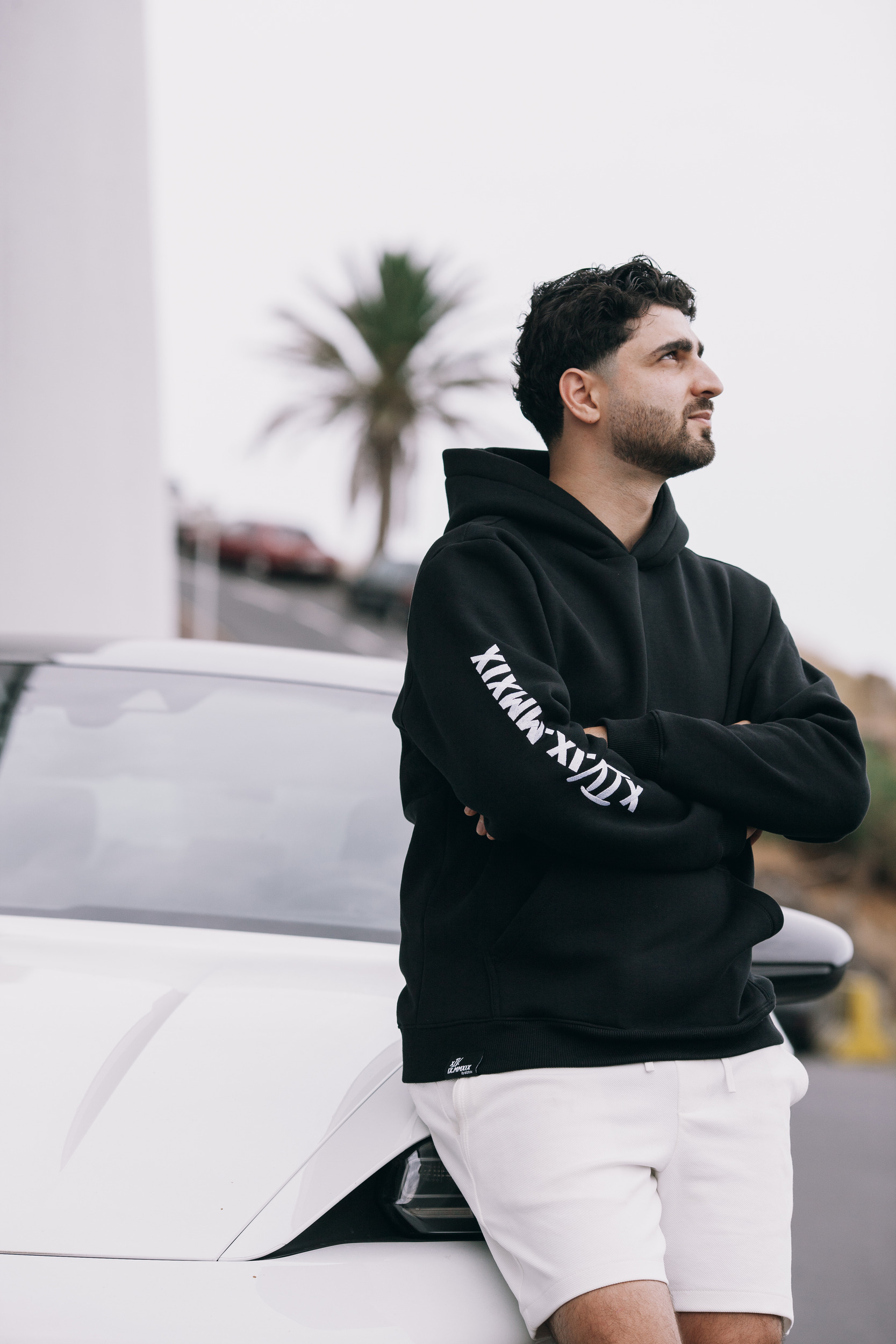Man in the black hoodie beside a white sports car, palms behind, Madeira