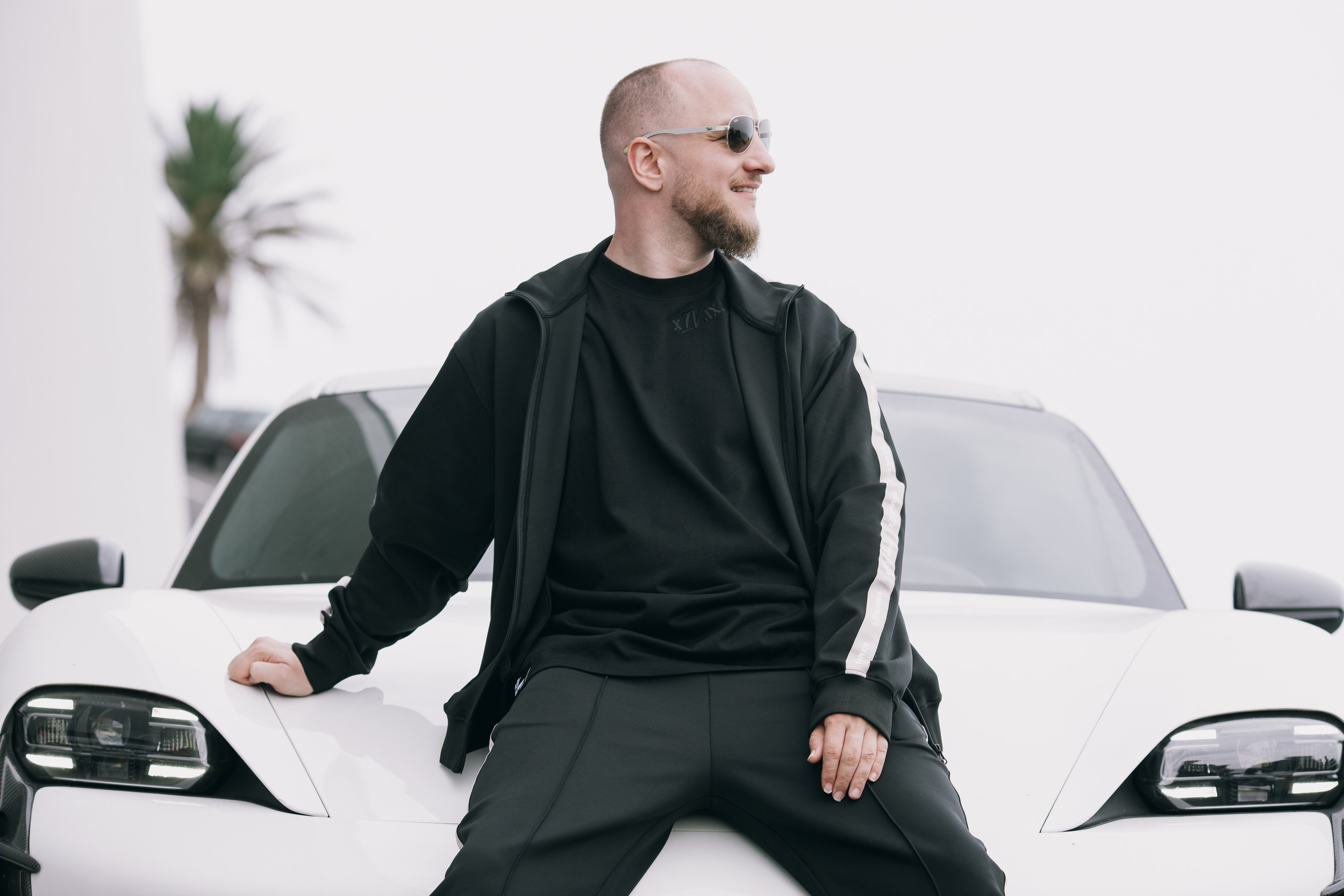Man sitting on the bonnet of the white sports car in the track jacket, Madeira