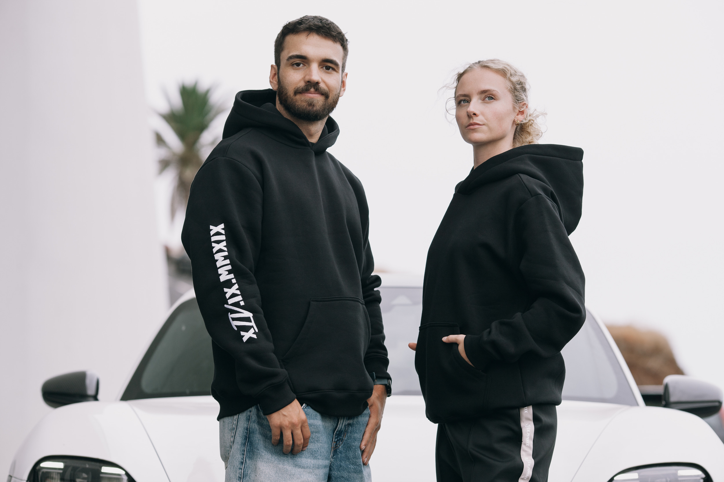 Man and woman in black hoodies standing by the white car, Madeira