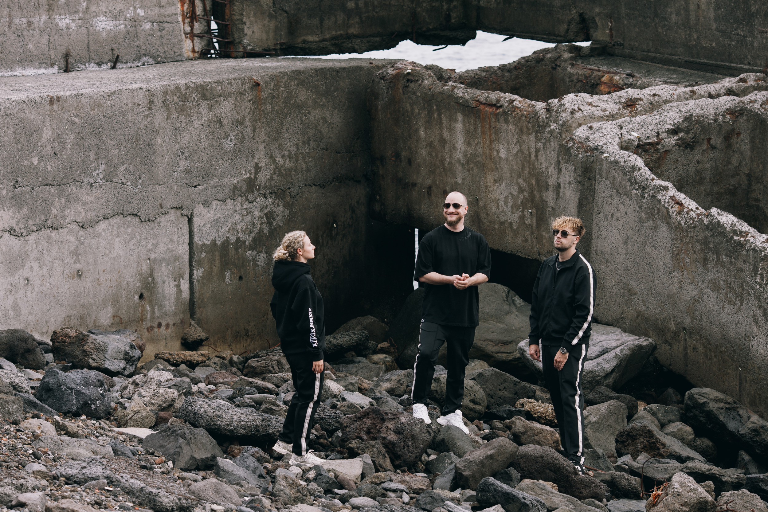 Three models standing on the rocks under the concrete deck near the airport runway, Madeira