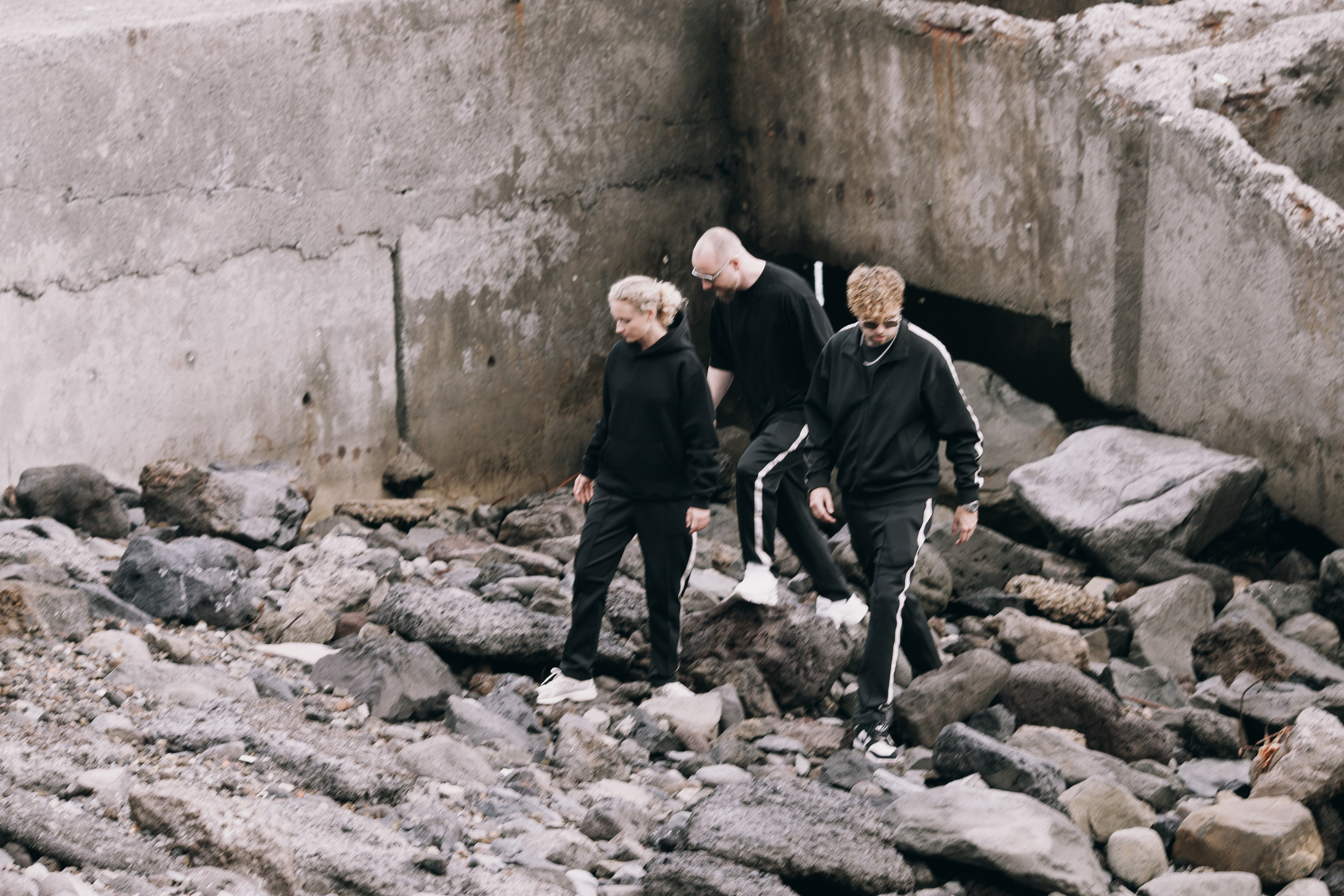 Three models climbing over the volcanic rocks under the concrete, Madeira