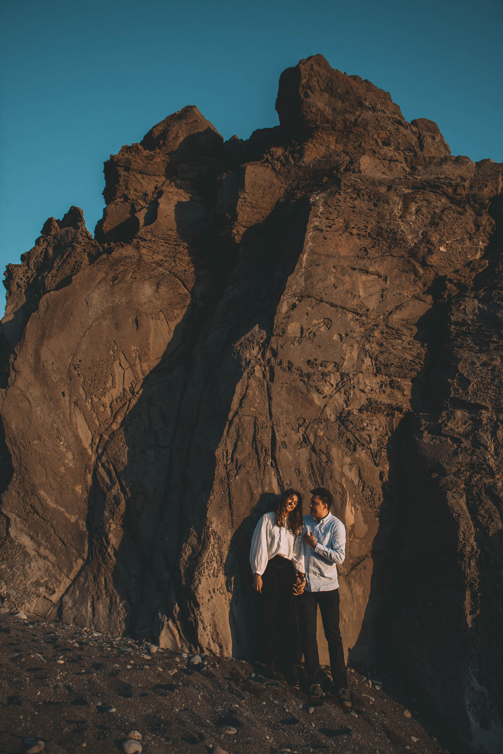 Couple on volcanic rocks at Praia Formosa, warm evening light, Funchal, Madeira