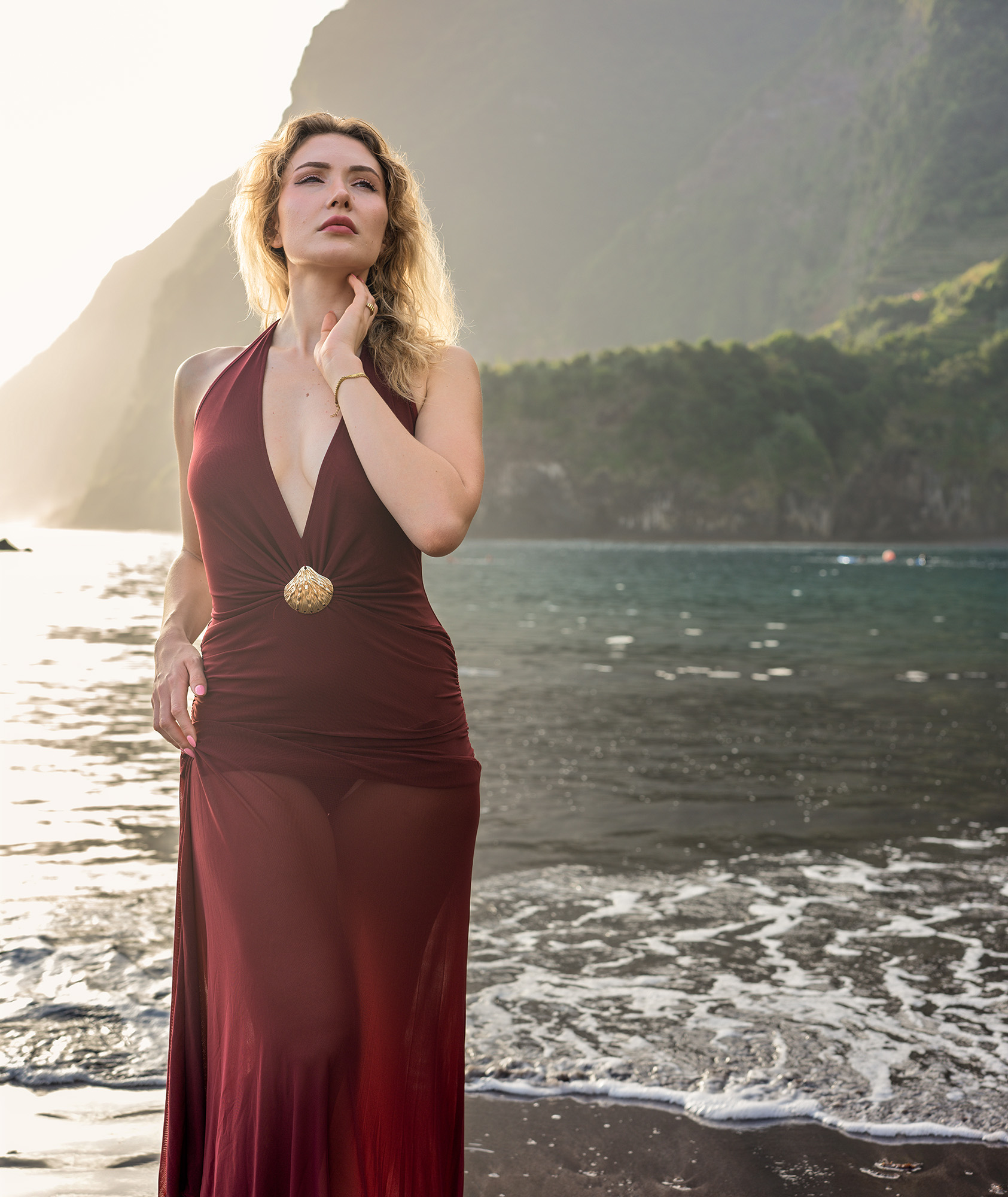 Woman in deep red dress against dark cliffs at Seixal Beach, Madeira