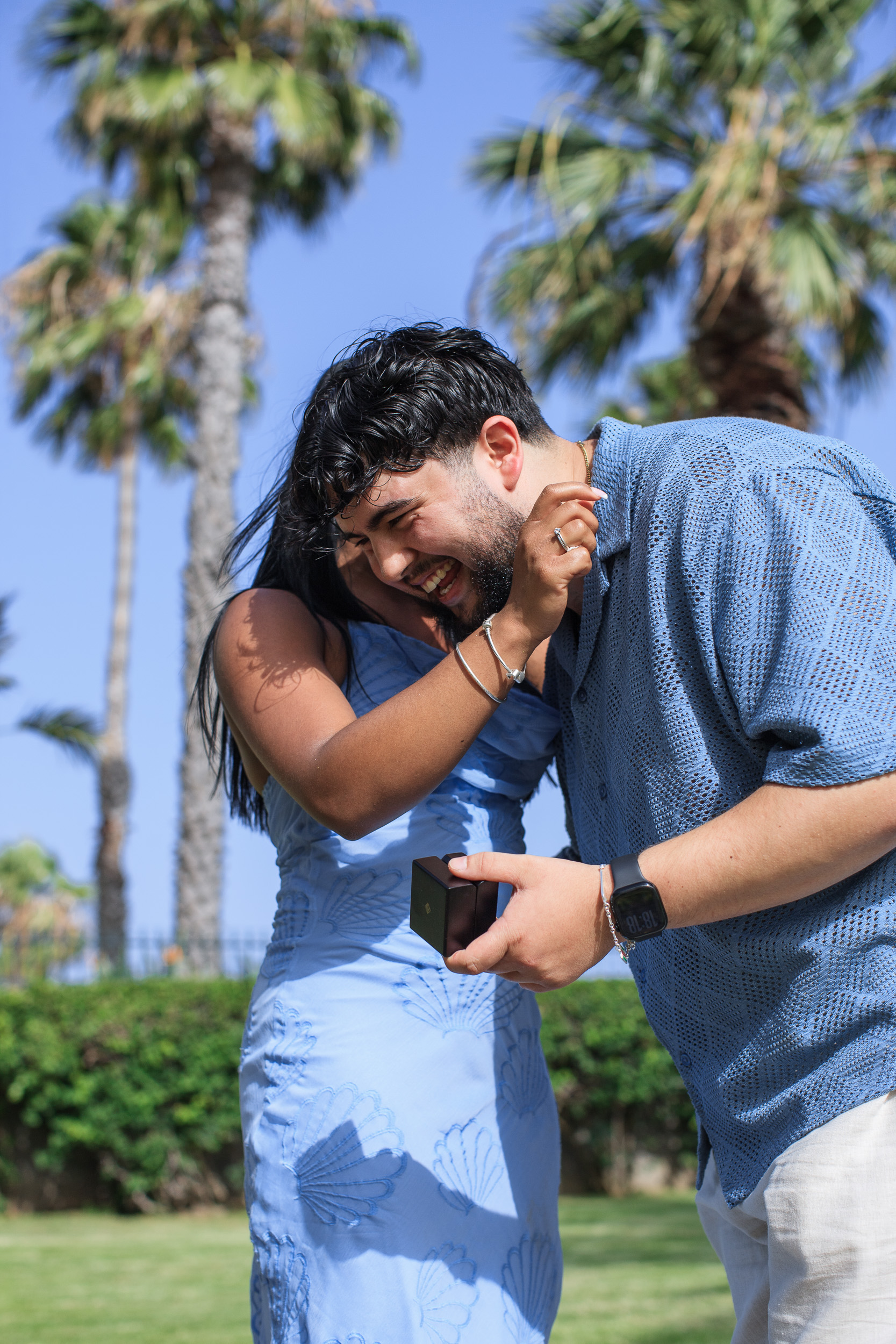 She hugs him from behind as he laughs with the ring box, Funchal, Madeira