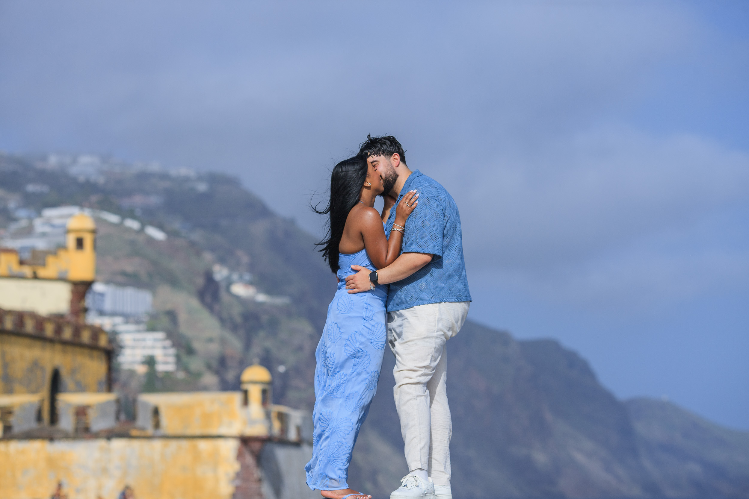 Embracing over the fort battlements with the hillside town behind, Funchal, Madeira