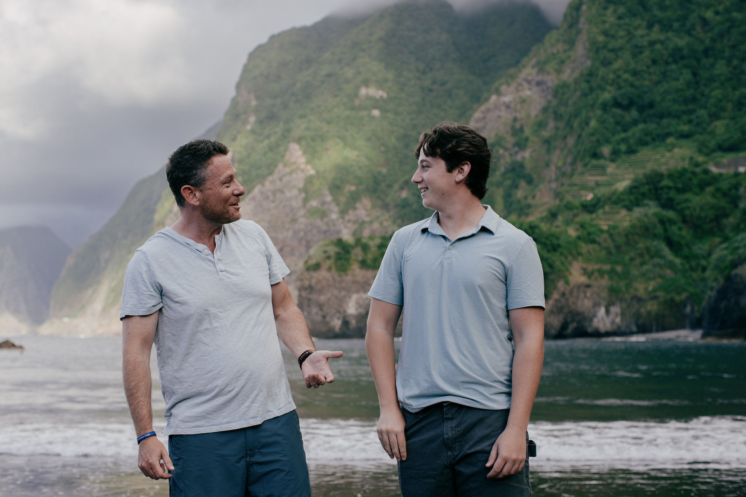 Father and son joking at the waterline below the cliffs, Seixal, Madeira