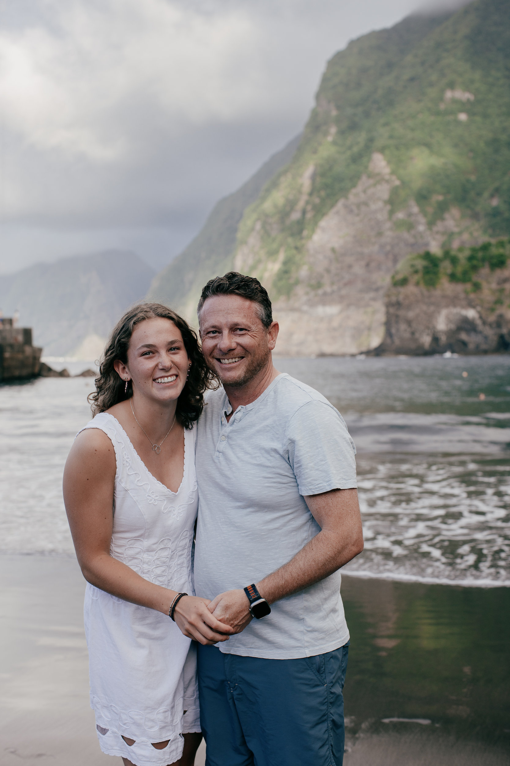 Daughter and father embracing on the wet sand at Seixal Beach, Madeira