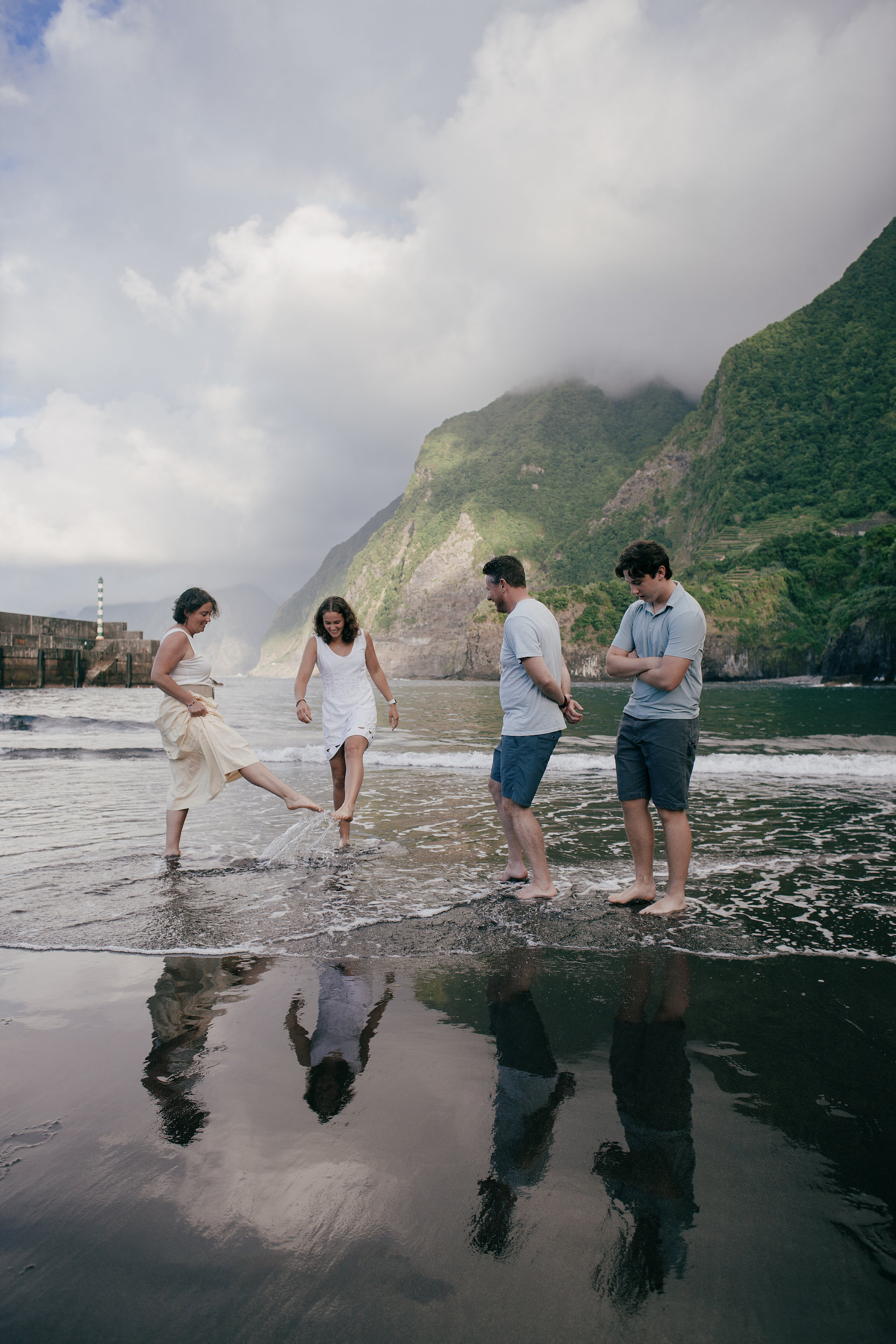 The family splashing through the shallows, reflections on the wet sand, Seixal, Madeira