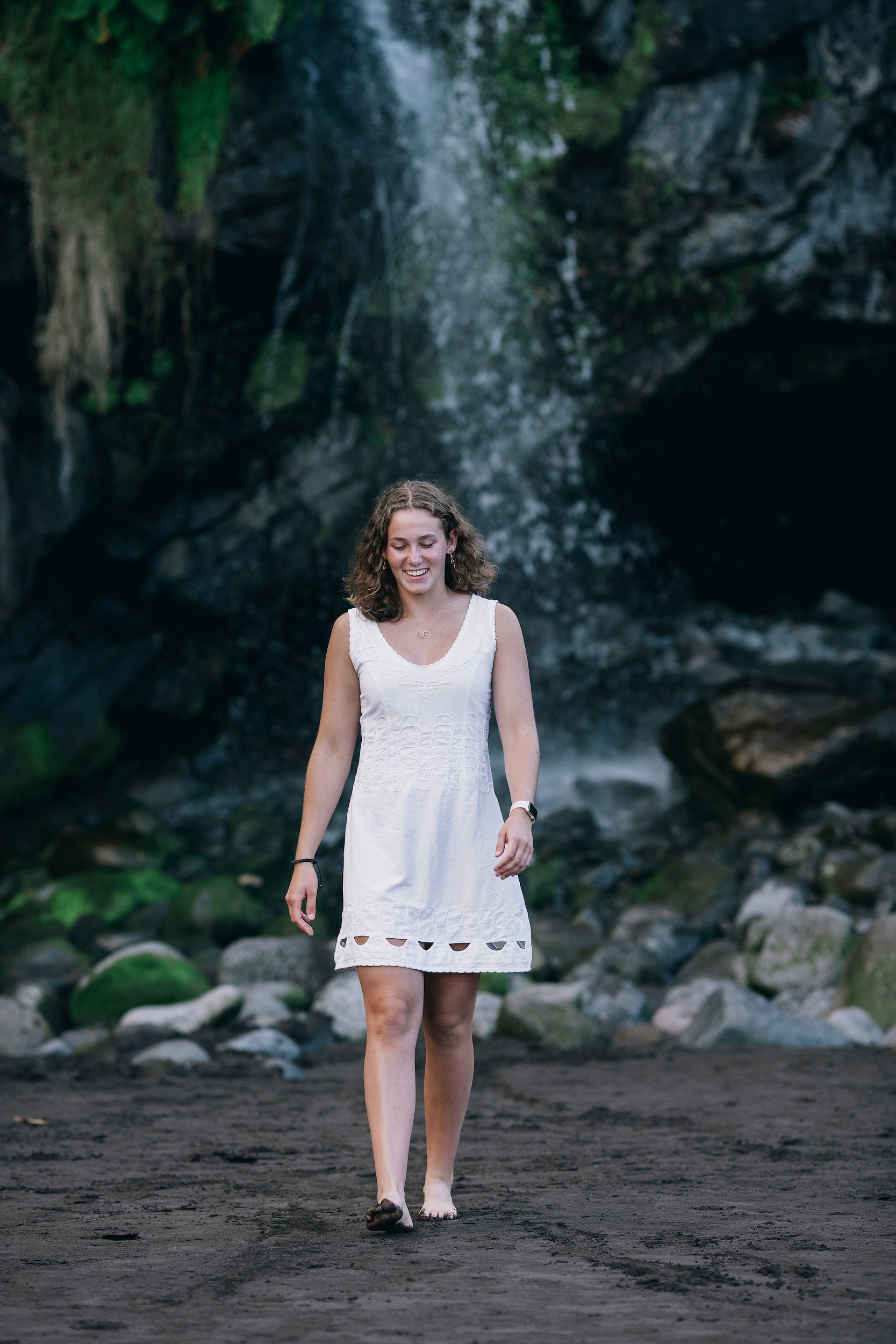 The daughter walking from under the waterfall at Seixal Beach, Madeira