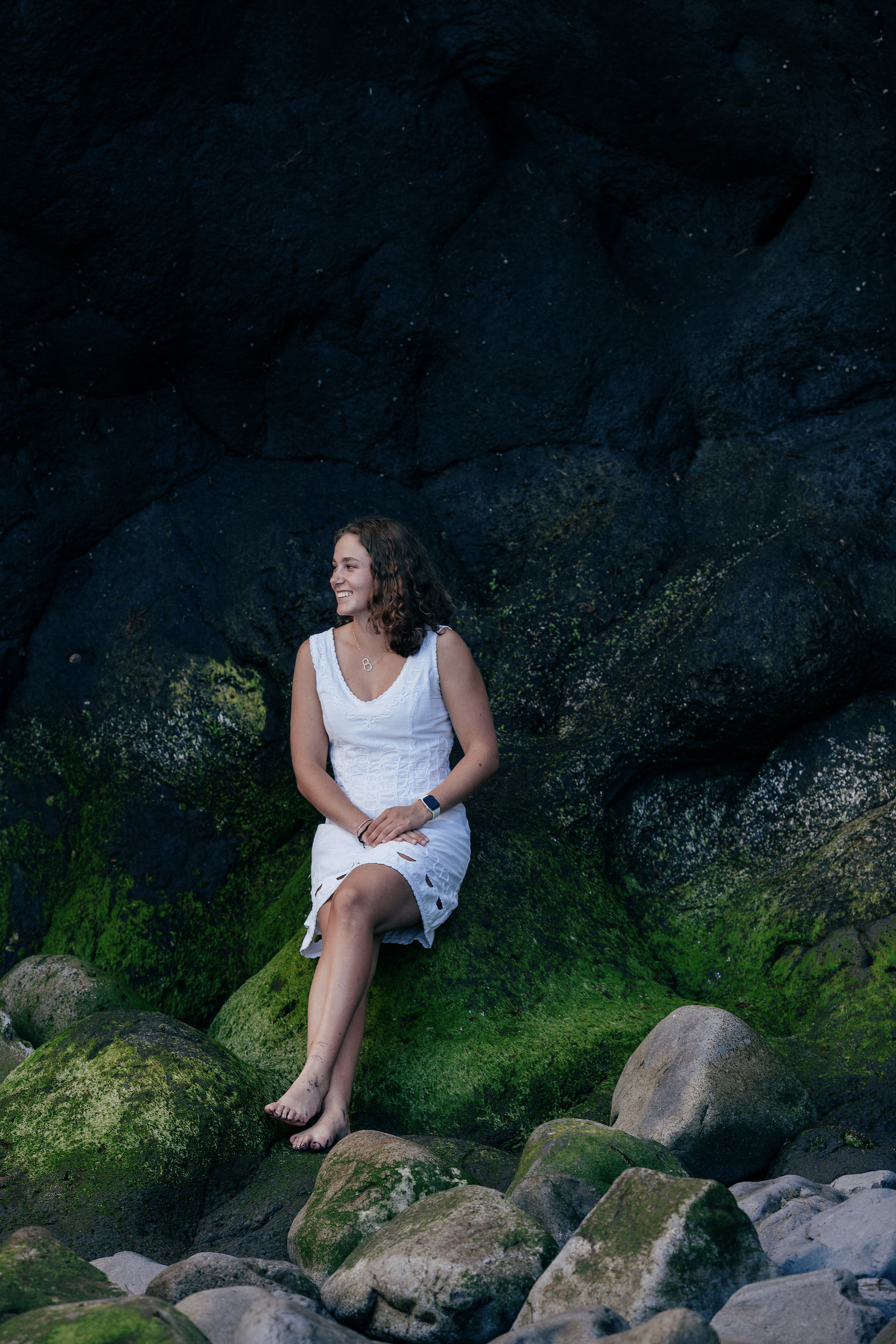 The mother seated on the moss-covered rocks in a white dress, Seixal, Madeira