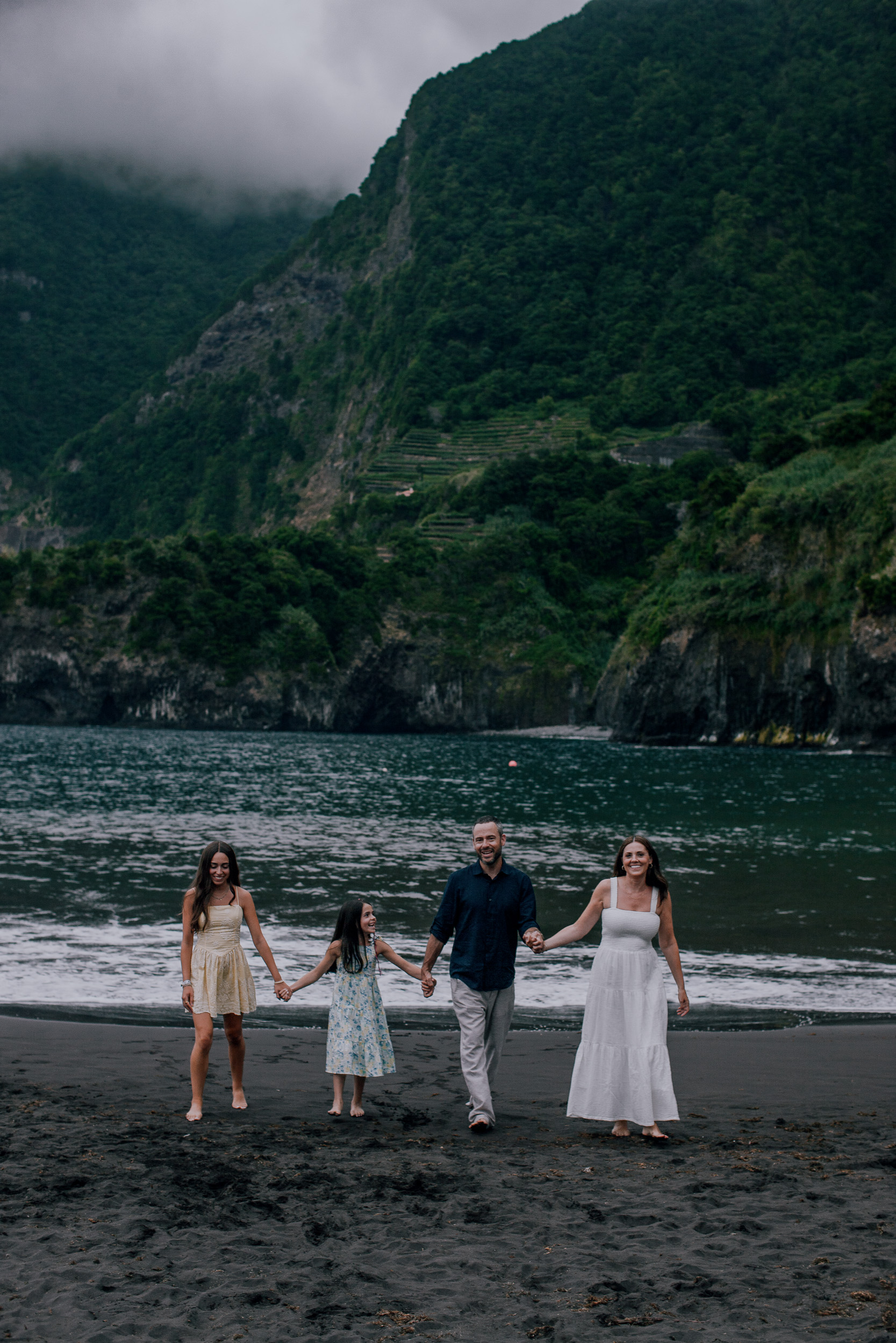 Parents and two daughters walking the black sand hand in hand, Seixal, Madeira