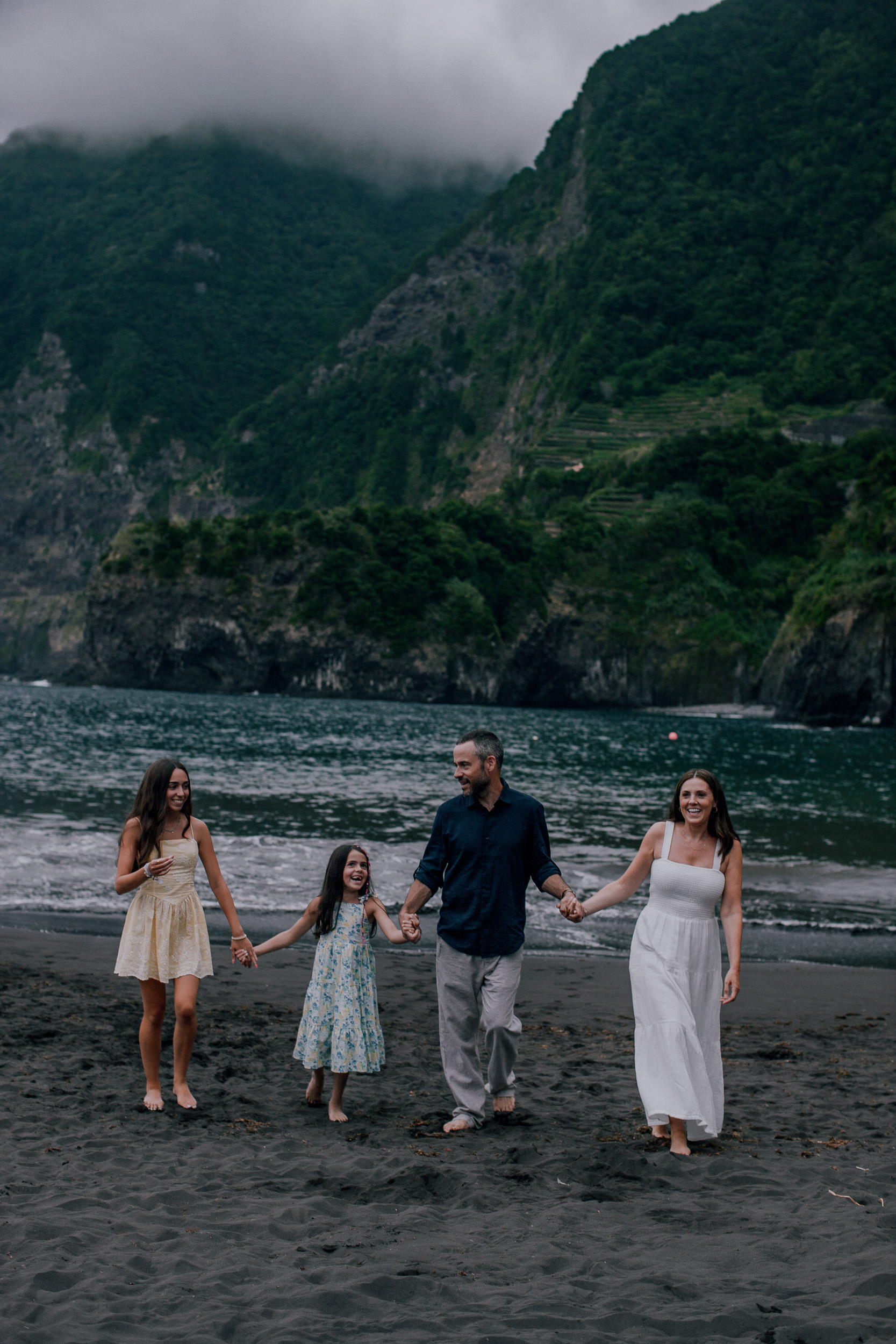 Hand in hand on the volcanic sand, evening clouds over the peaks, Seixal, Madeira