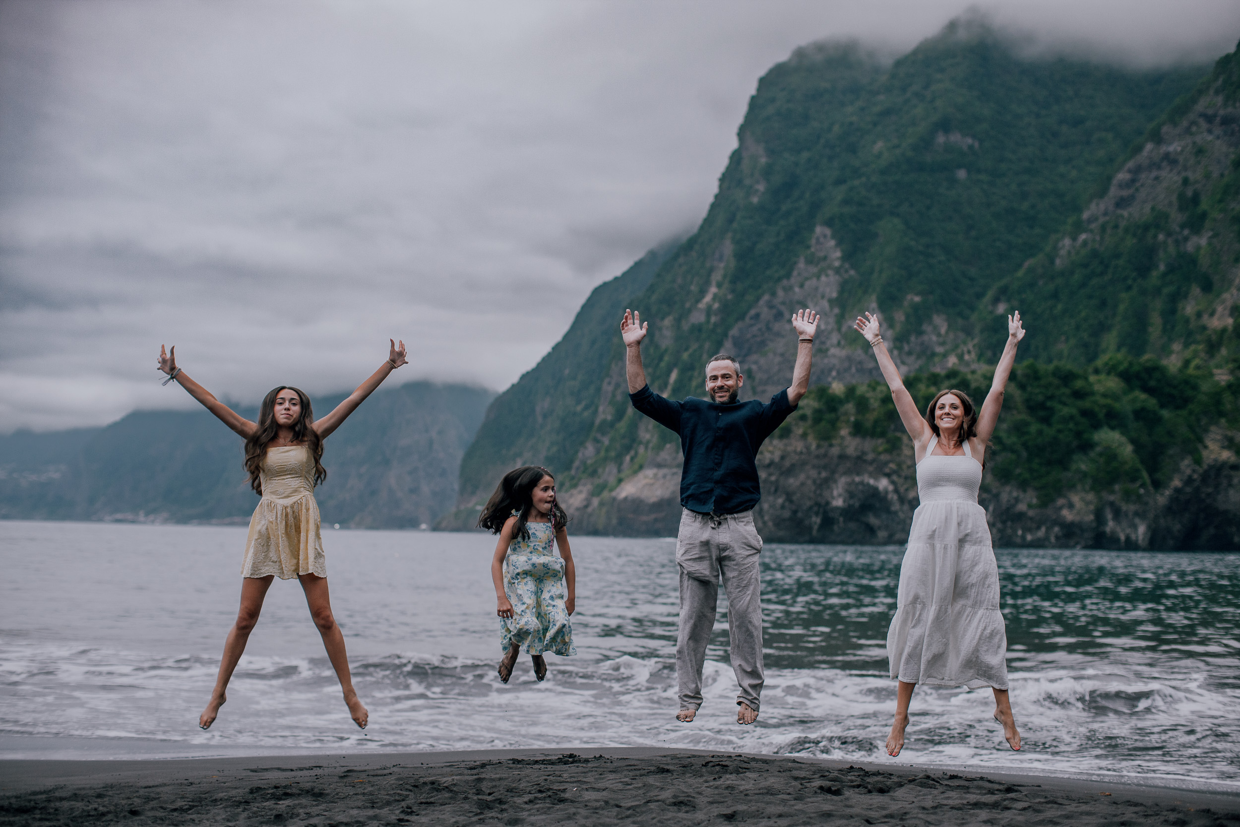 All four jumping with arms raised on the beach, Seixal, Madeira
