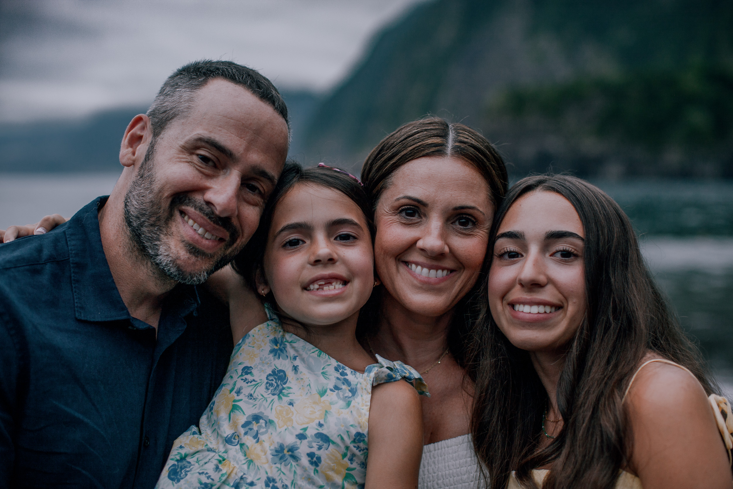 Family faces close together smiling, dark cliffs behind, Seixal, Madeira