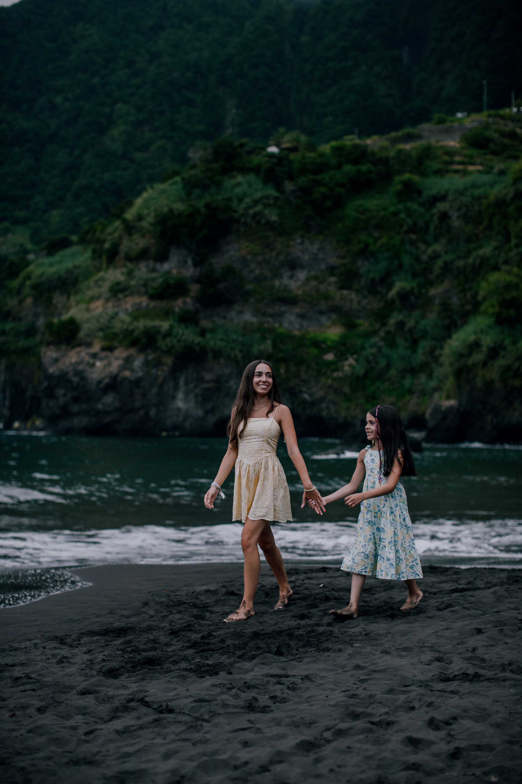 Mother and daughter hand in hand at the water, Seixal Beach, Madeira