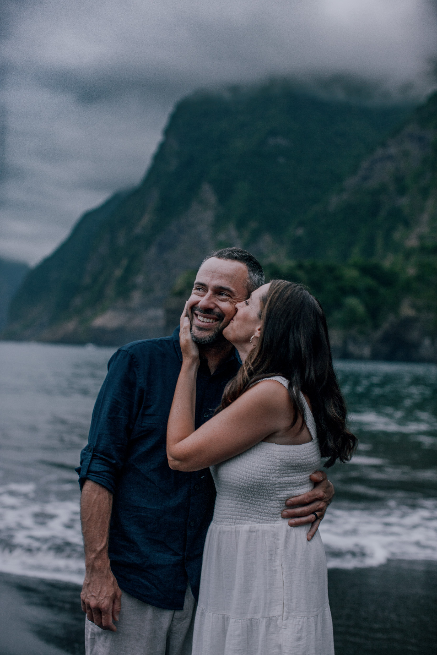 She kisses his cheek at the waterline, evening at Seixal, Madeira