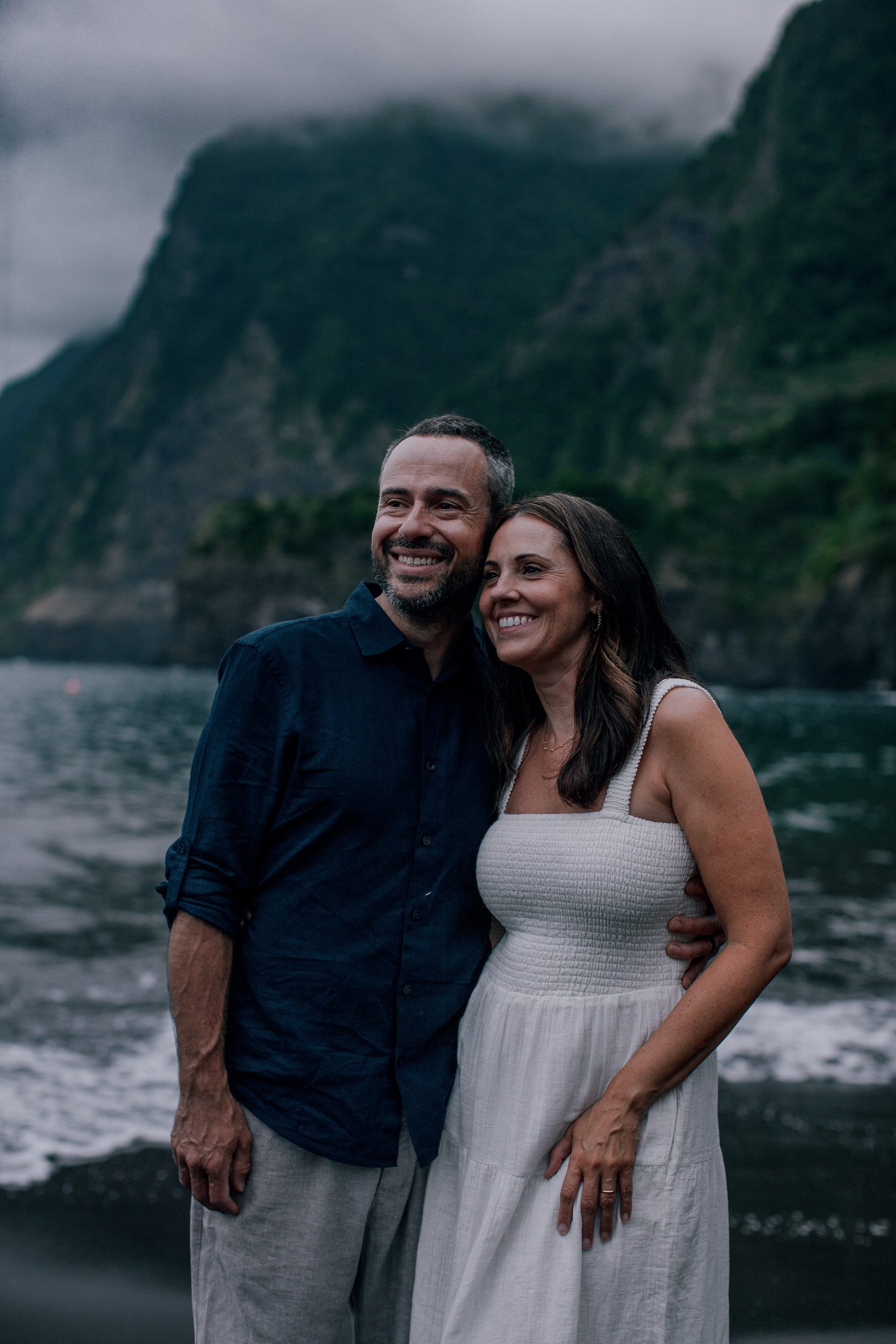 The couple smiling together on the dark beach, Seixal, Madeira
