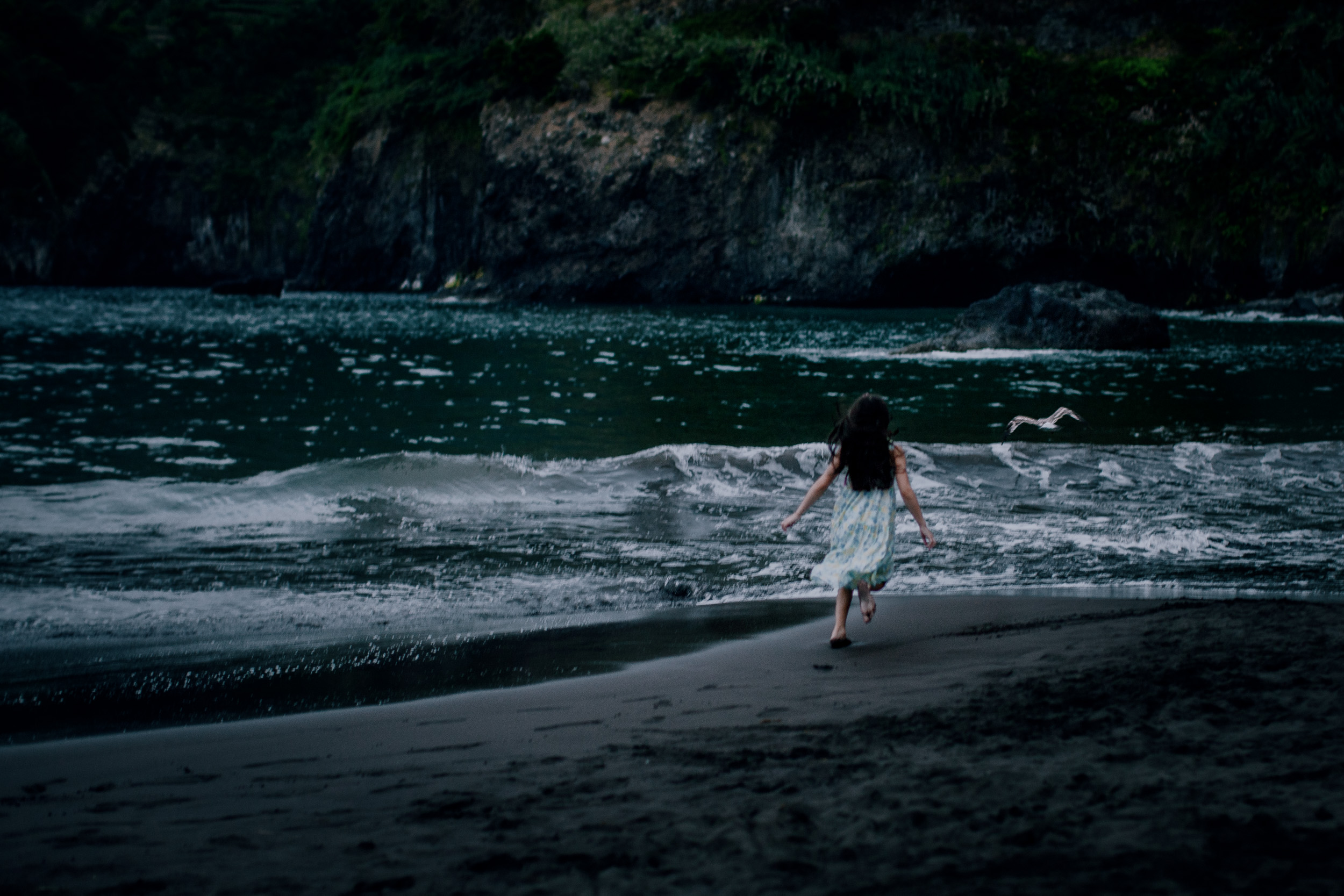 The younger daughter running the empty dark shore, Seixal, Madeira
