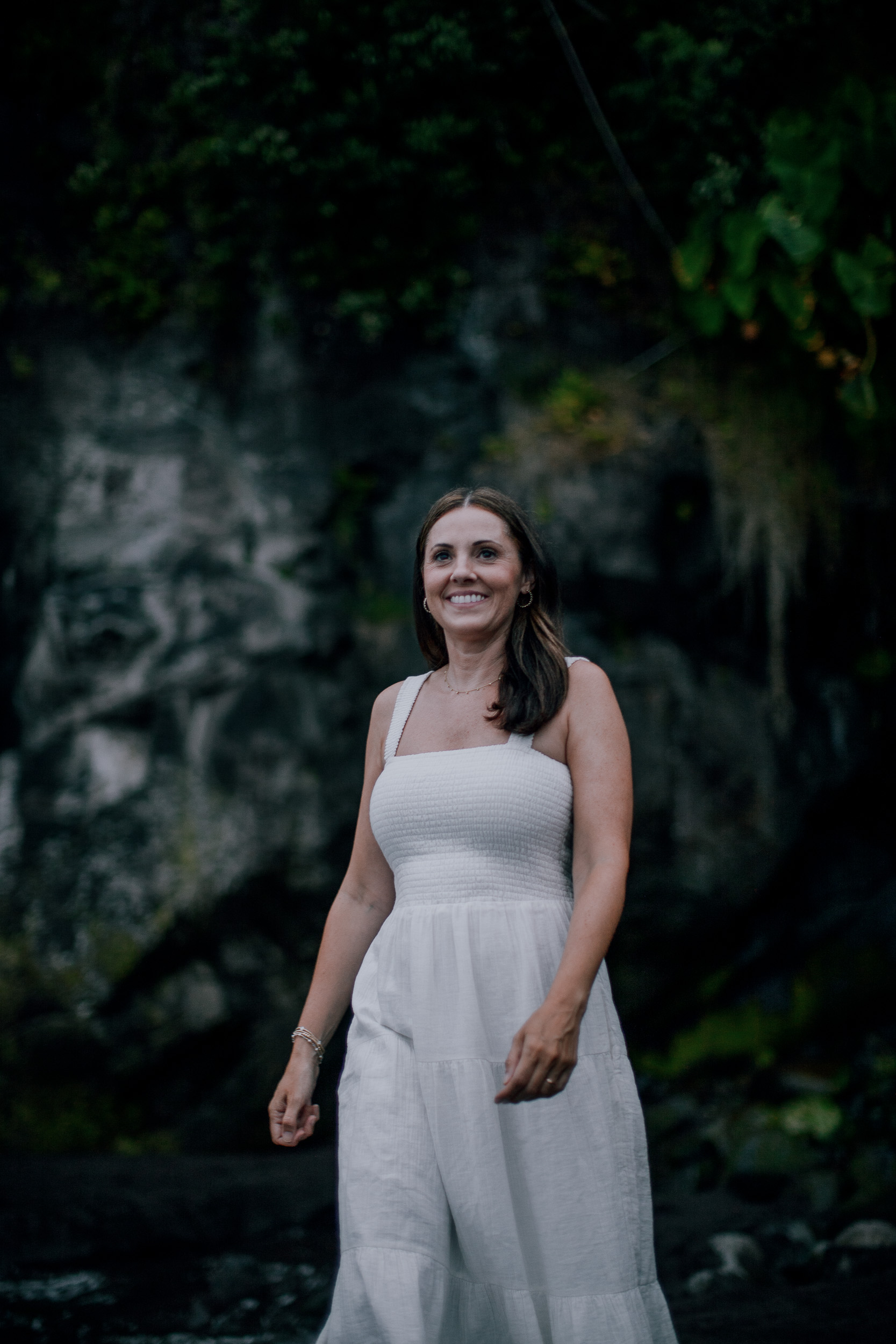 The mother in white by the mossy rock face, Seixal, Madeira