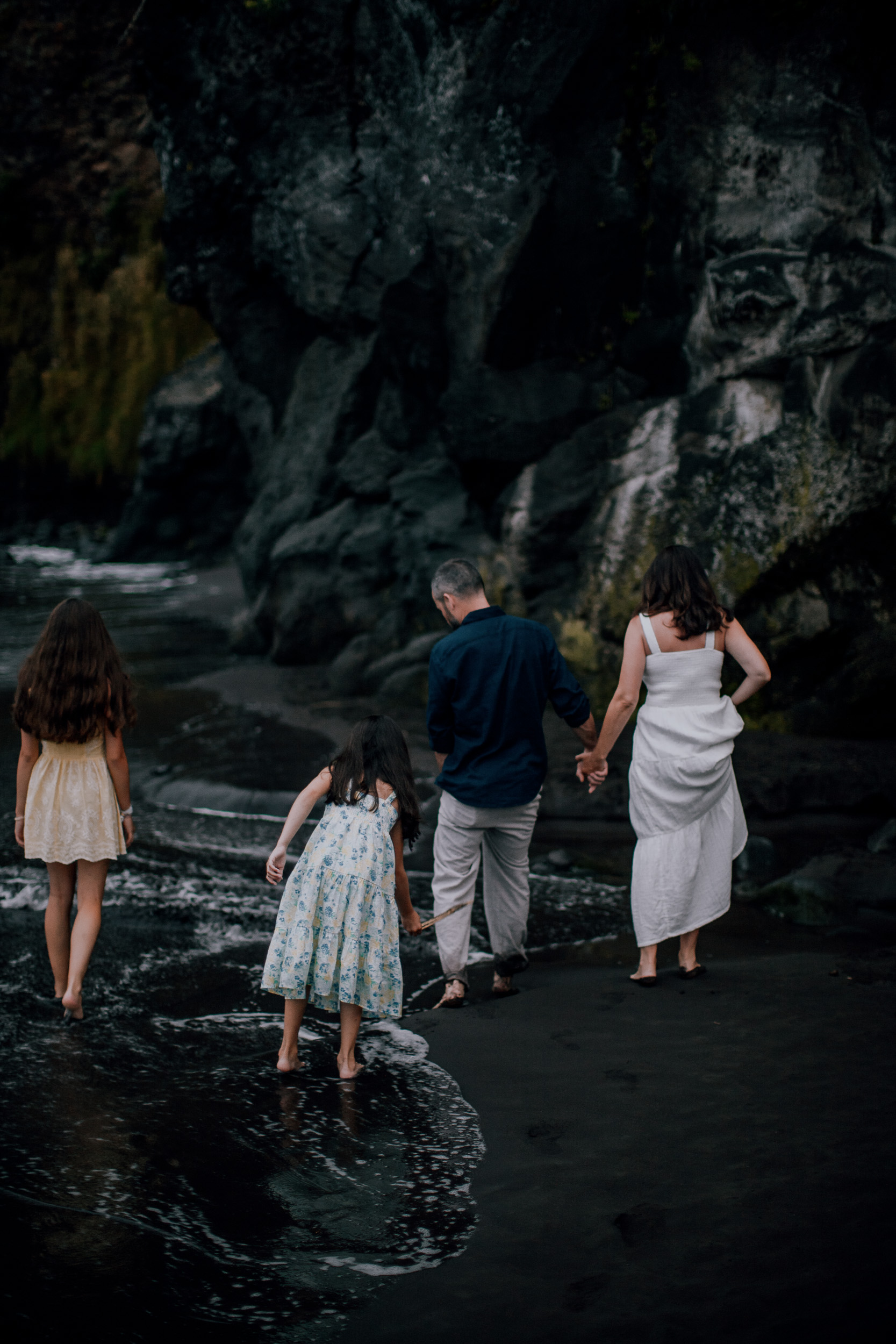 The family walking into the cave shadow at the beach end, Seixal, Madeira