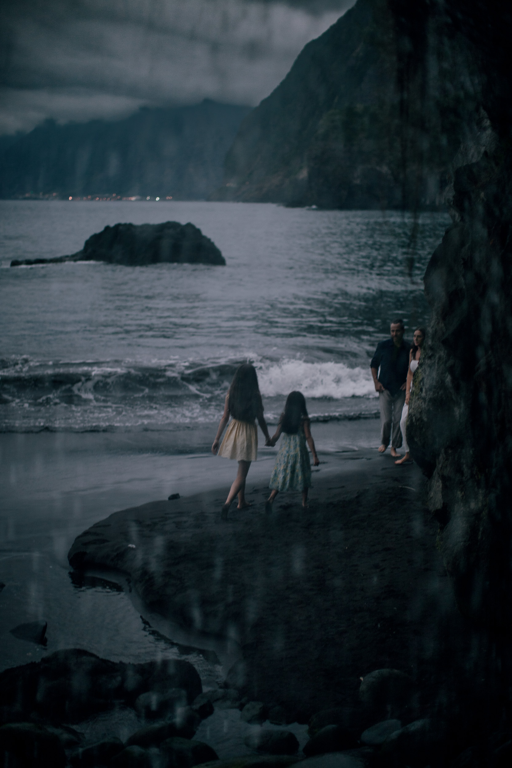 Mother and daughter at the water by the sea stack, dusk at Seixal, Madeira